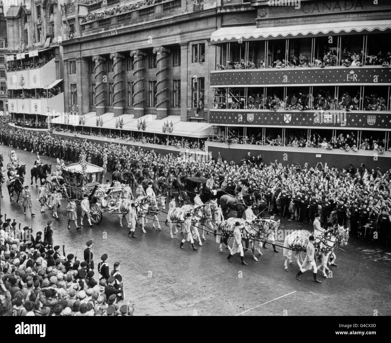 La procession du couronnement au retour de l'abbaye de Westminster au palais de Buckingham. L'entraîneur d'État passe devant l'entraîneur de Sir Winston Churchill qui a dû tomber complètement et qui a été tenu à l'extérieur de la Maison du Canada. Banque D'Images