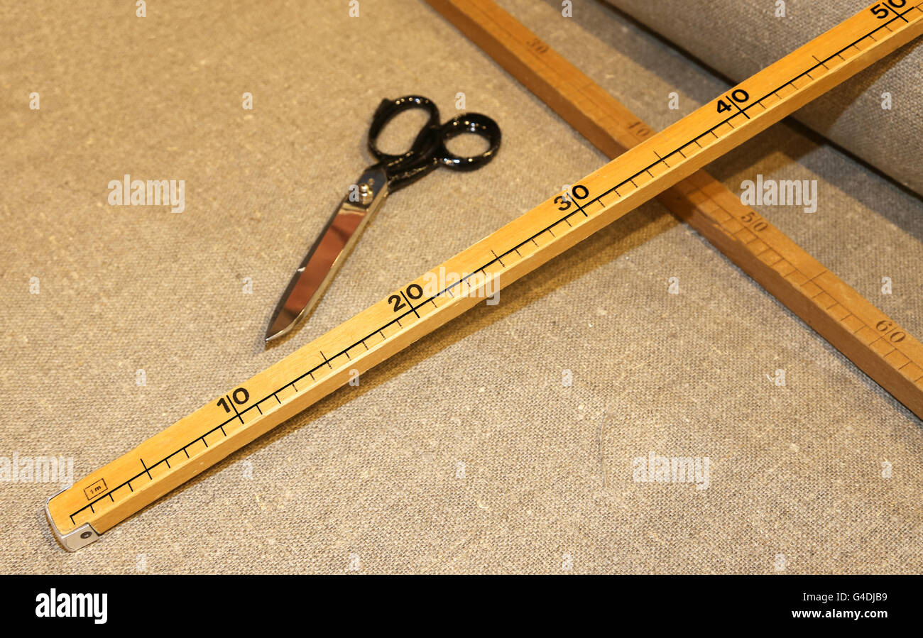Les grands ciseaux du tailleur avec le mètre en bois dans la confection artisanal italien Banque D'Images