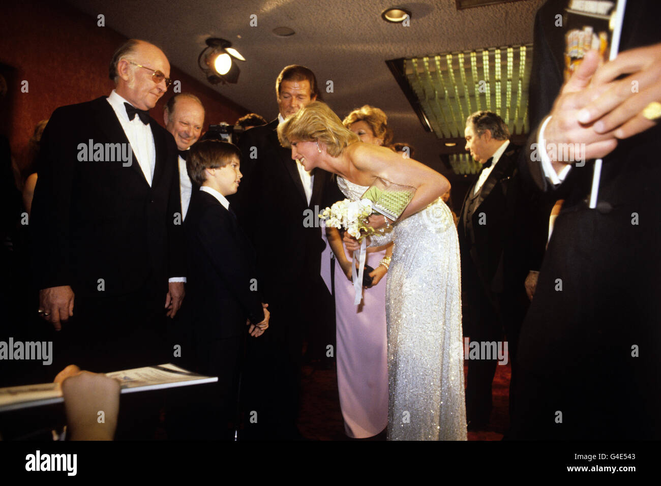 Christopher Moore, âgé de 11 ans, fils de l'acteur Roger Moore de James Bond, rencontre la princesse de Galles lors de la première de la Royal World Charity du nouveau film Bond, Octopussy. Le producteur de film Albert Broccoli est à gauche. Banque D'Images