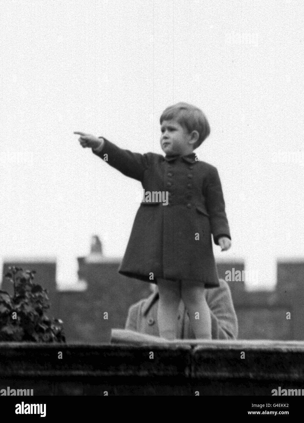 LE PRINCE DE GALLES SUR LE MUR DE CLARENCE HOUSE, LONDRES COMME LA REINE ET LE DUC D'ÉDIMBOURG PASSENT DANS UNE CALÈCHE OUVERTE PENDANT LEUR TRAJET EN PROCESSION DE BUCKINGHAM PALACE À GUILDHALL POUR RECEVOIR L'ACCUEIL OFFICIEL DE LA VILLE À SON RETOUR DE LEUR VISITE DU CANADA Banque D'Images