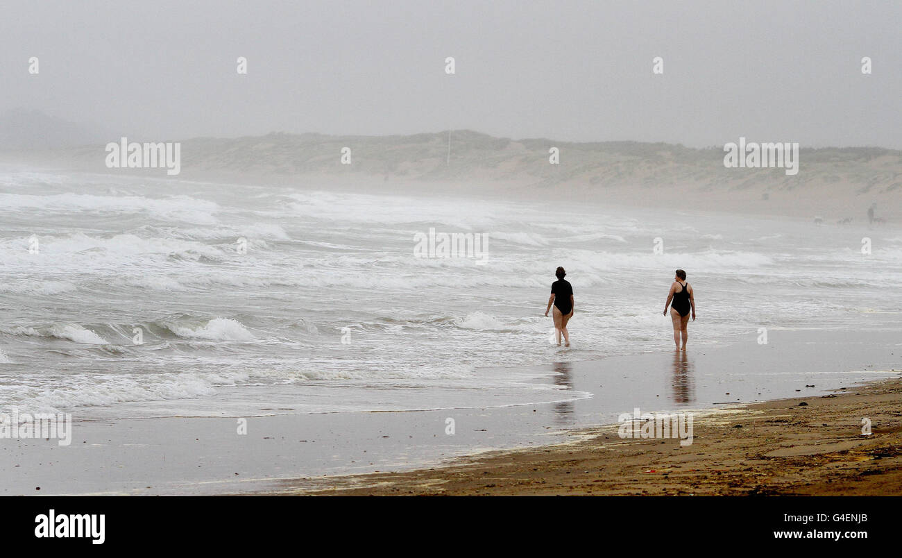 Deux femmes brave la mer près de Camber dans l'est du Sussex, tandis que de fortes averses de pluie balaient le pays. Banque D'Images