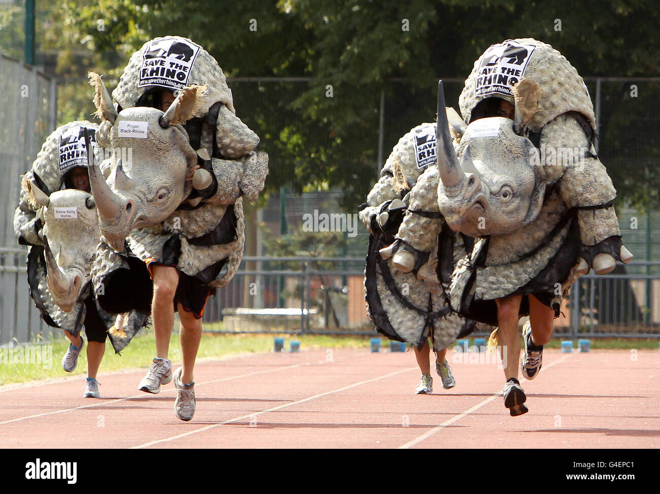 Les coureurs vêtus de costumes de rhinocéros prennent part à un sprint de 100 mètres, organisé par Save the Rhino International, au Mile End Park Stadium, à l'est de Londres, pour souligner le travail de l'association caritative, qui accueille des populations de rhinocéros en danger critique en Afrique et en Asie. Banque D'Images