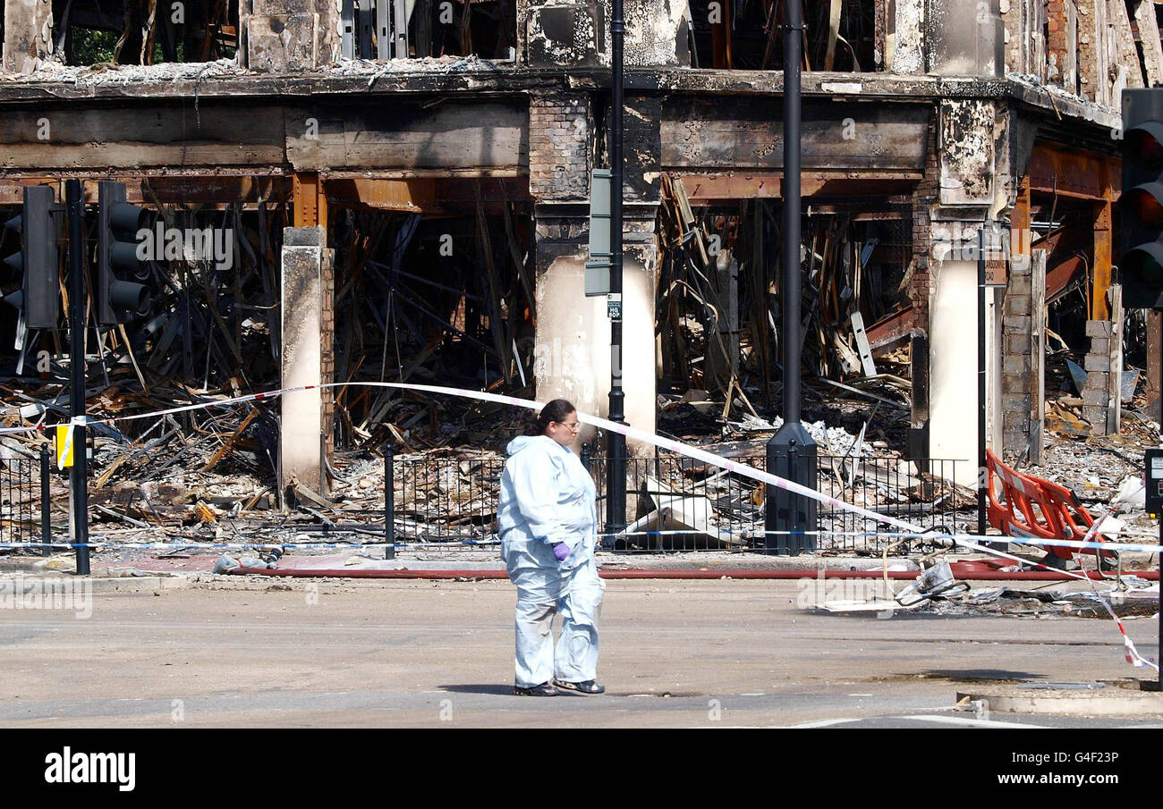 Des scènes d'officiers du crime se promeuillent devant un bâtiment incendié détruit lors des émeutes et des pillages sur la route Tottenham High Road pendant le week-end. Banque D'Images