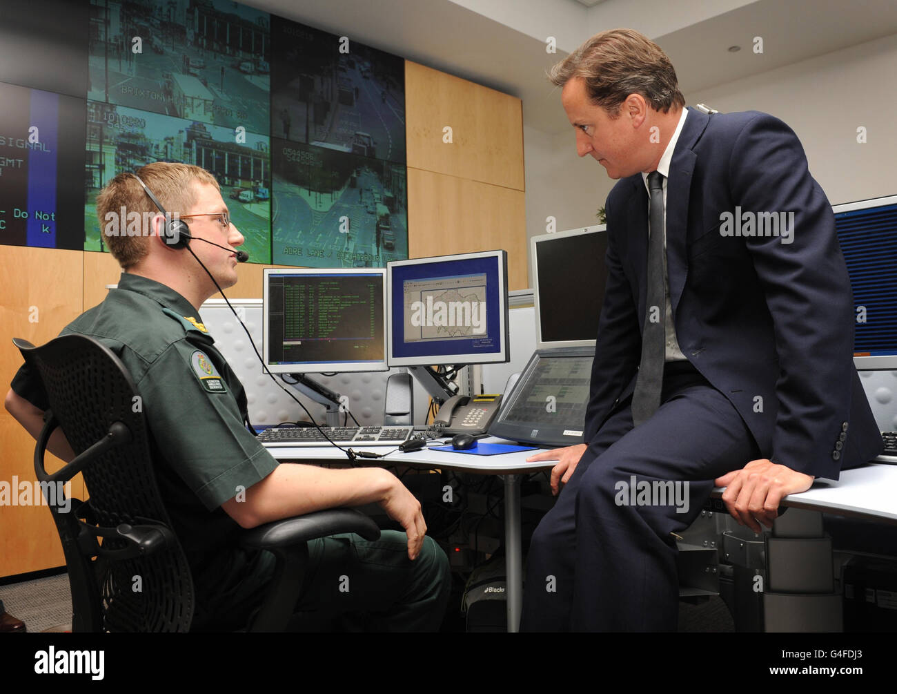 RETRANSMISSION, précisant que l'agent est du London Ambulance Service. Le Premier ministre David Cameron s'entretient avec un officier du Service d'ambulance de Londres lors d'une visite au quartier général du Commandement de l'or de la police métropolitaine à Lambeth, dans le sud de Londres, après avoir coupé court de ses vacances pour prendre en charge la réponse du gouvernement à trois jours d'émeutes dans la capitale et ailleurs. Banque D'Images