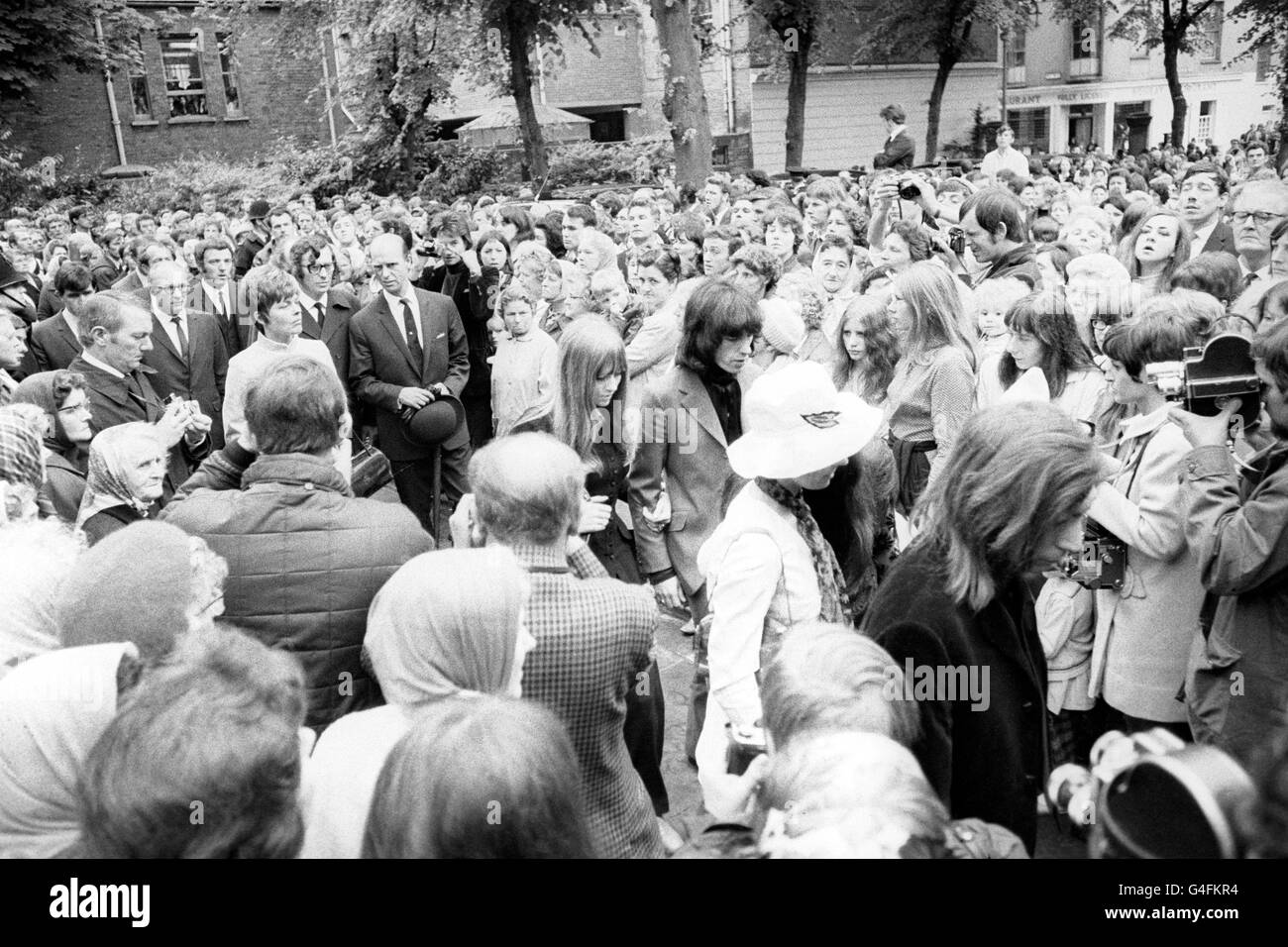 Rolling Stones Charlie Watts (caméra plus proche) an d Bill Wyman passer les fans silencieux alors qu'ils arrivent à l'église paroissiale de Cheltenham pour assister au service funéraire pour Brian Jones, ancien guitariste de 27 ans avec les Rolling Stones. Banque D'Images