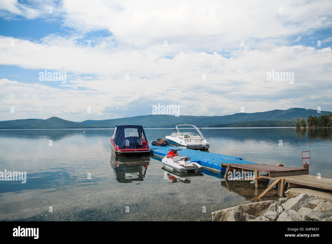 Les bateaux à moteur sont à quai au lac. ciel bleu, montagne et forêt Banque D'Images