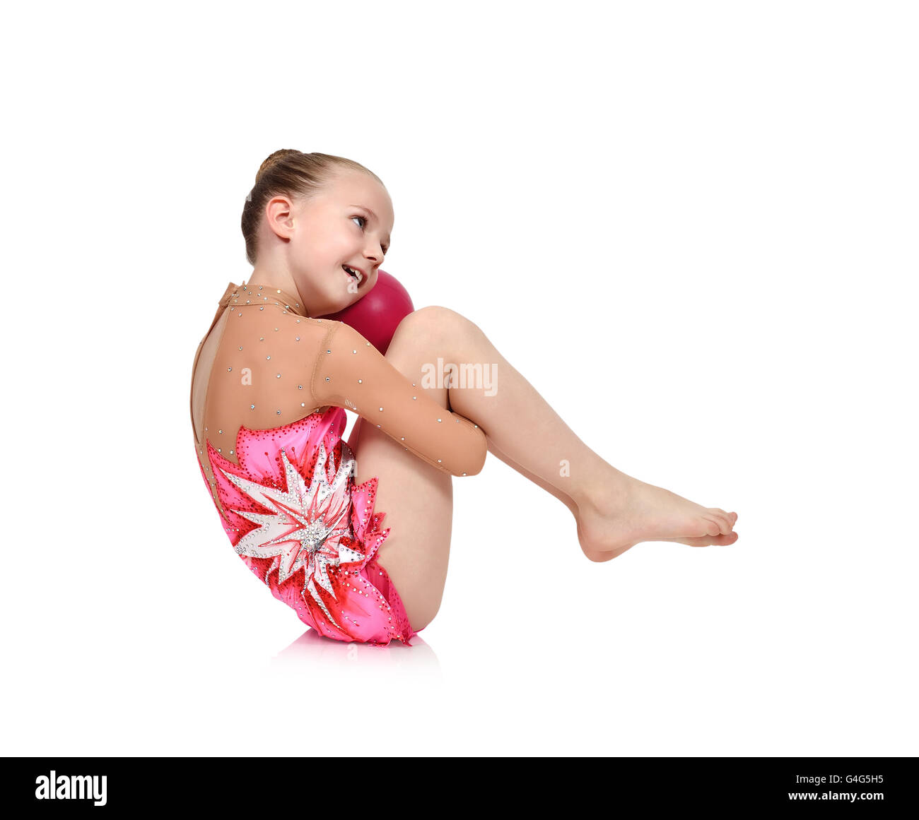 Petite fille gymnaste en rouge vêtements posant avec la balle Banque D'Images
