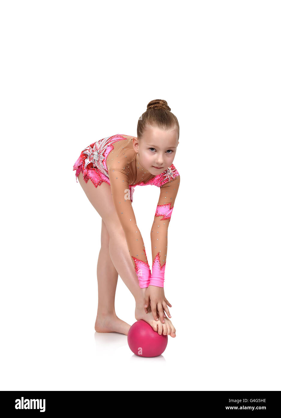 Jeune fille en vêtements rose faisant la gymnastique avec boule rouge Banque D'Images