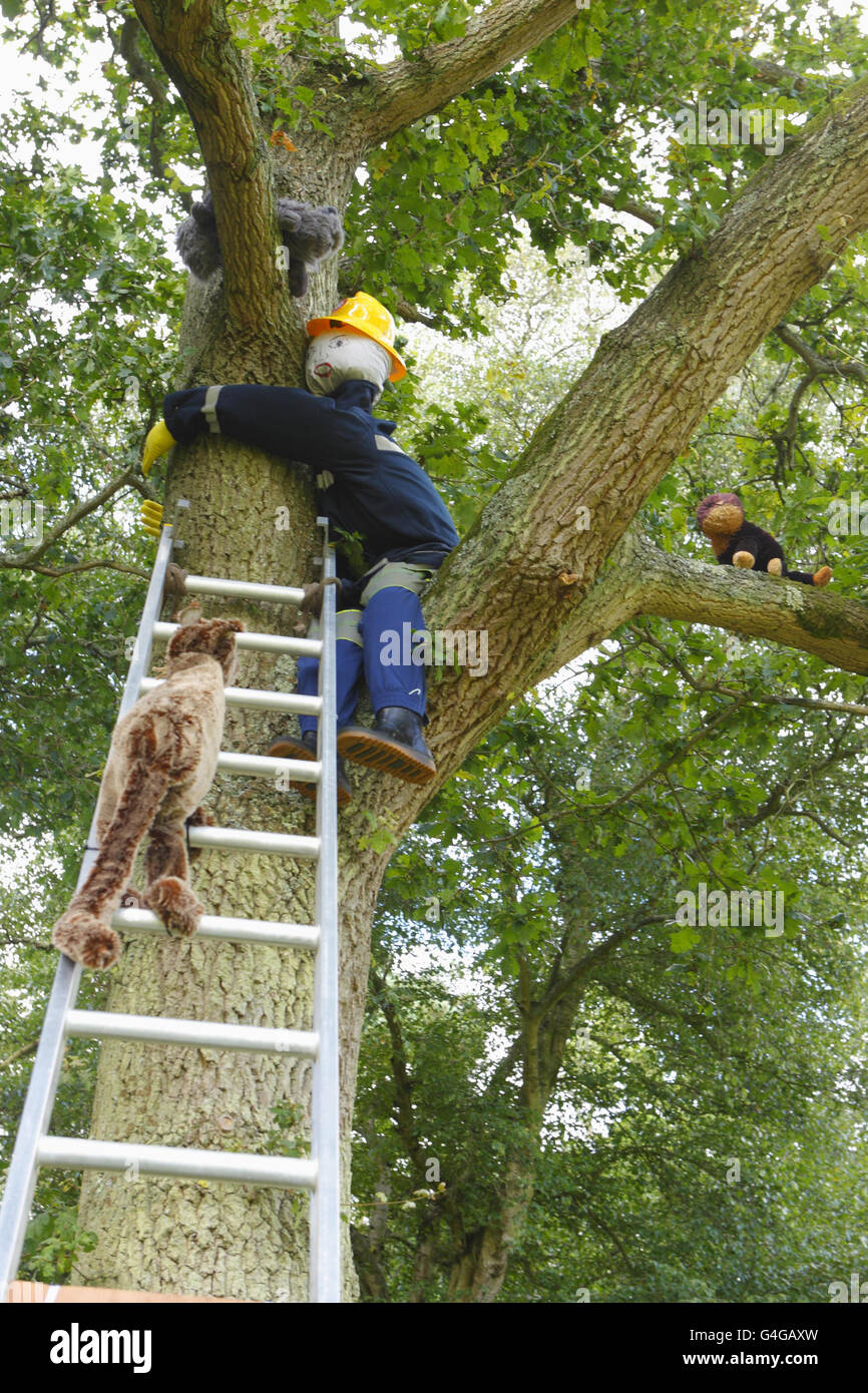 Un pompier de paille tente de secourir trois chats au festival de Bisterne Scarecrow près de Ringwood, dans le Hampshire. Banque D'Images