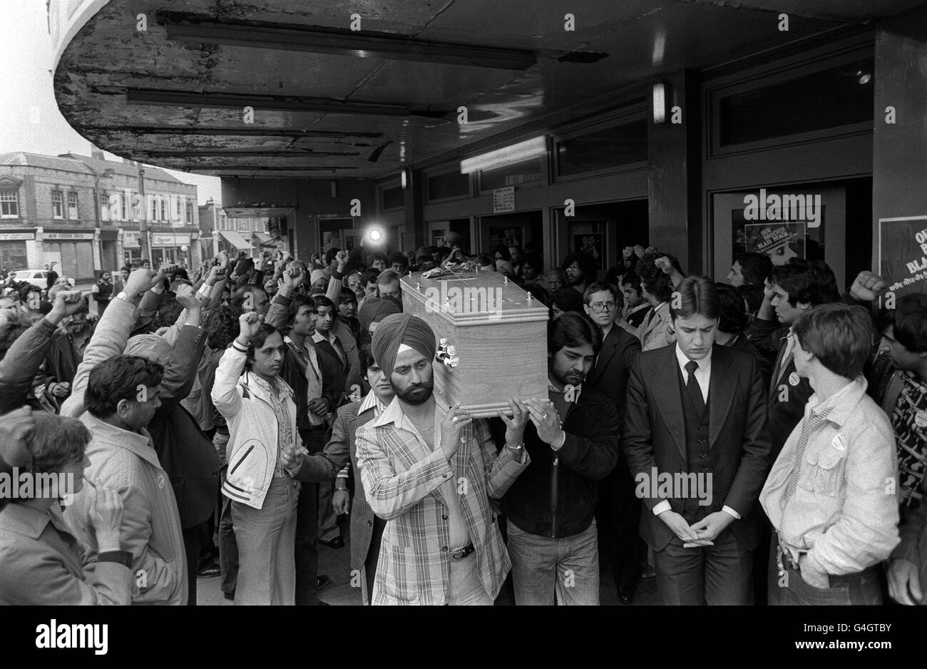 PA NEWS PHOTO 13/6/79 LES AMATEURS DE TOURNANTS LÈVENT LEURS MAINS DANS DES SAUTES SERRÉS COMME LE CERCUEIL PORTANT LE CORPS DE L'ENSEIGNANT BLAIR PEACH EST PORTÉ PAR 10 PALLBEARERS ASIATIQUES DU CINÉMA DOMINON À SOUTHALL LORS DE SON DERNIER VOYAGE VERS LE CIMETIÈRE DE L'EST DE LONDRES OÙ IL SERA ENTERRÉ. M. PEACH, UN NOUVEAU ZEALANDER DE 31 ANS QUI A ENSEIGNÉ DANS UNE ÉCOLE DE L'EST DE LONDRES, EST DÉCÉDÉ DES SUITES DE BLESSURES À LA TÊTE LORS DE LA MANIFESTATION DE FRONT ANTI-NATIONALE À SOUTHALL IL Y A SEPT SEMAINES Banque D'Images