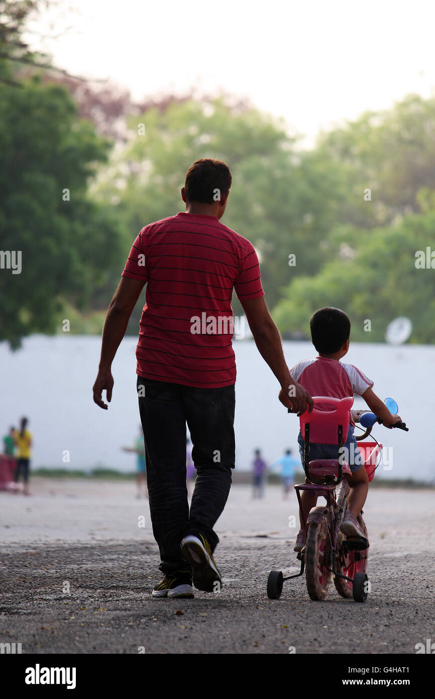 Jeune garçon, aidé par son père, apprendre à utiliser son vélo pour les enfants. Banque D'Images