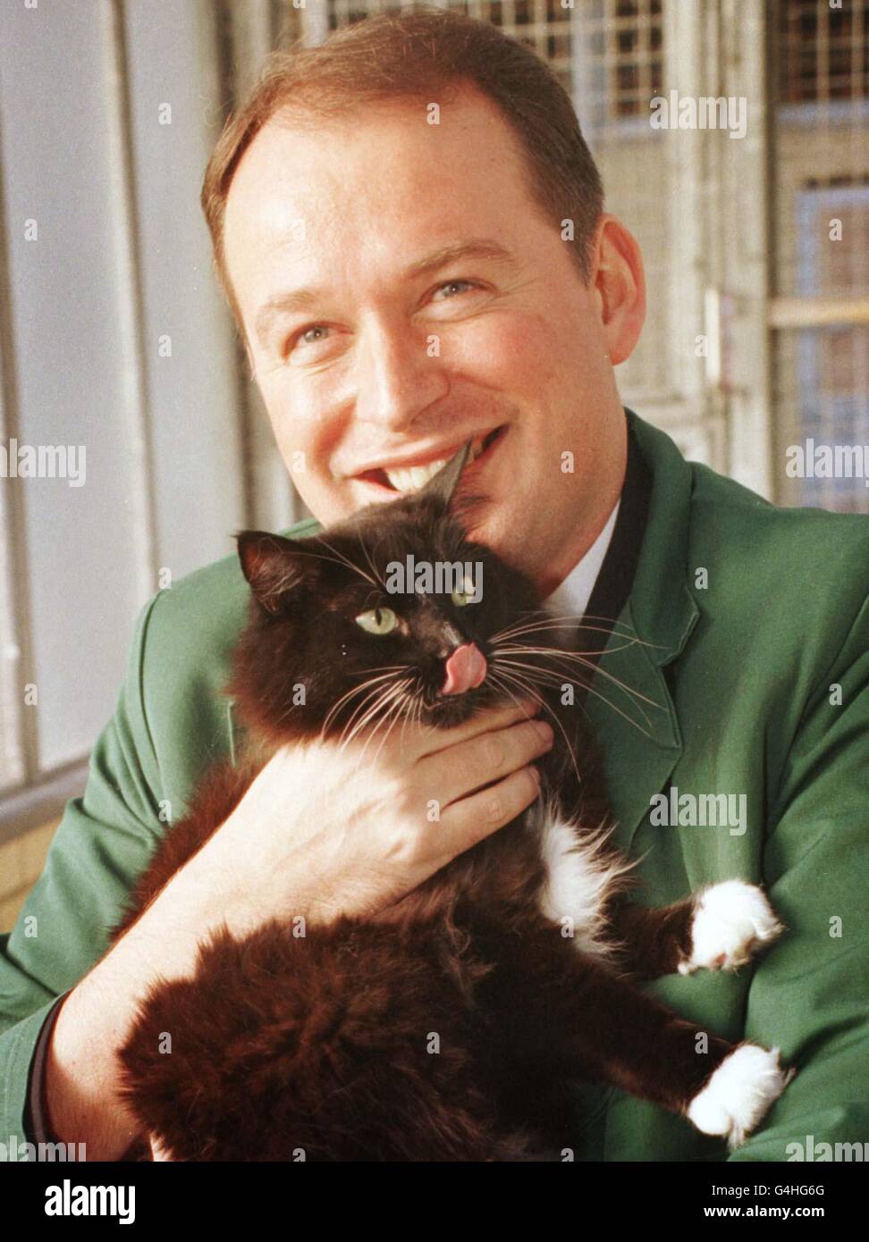 John Pearson, un steward de British Airways, câline son chat, Katie, au Animal Quarantine Center, à l'aéroport de Heathrow, le vendredi 4 décembre 1998.Katie - qui ne passe pas normalement devant le jardin de M. Pearson - a effectué une traversée transatlantique non programmée de sept heures vers Montréal après avoir été poignardé dans sa valise.British Airways paie le coût de son séjour en quarantaine en 1,000.Voir PA Story TRANSPORT CatPhoto PA Tim Ockenden. Banque D'Images