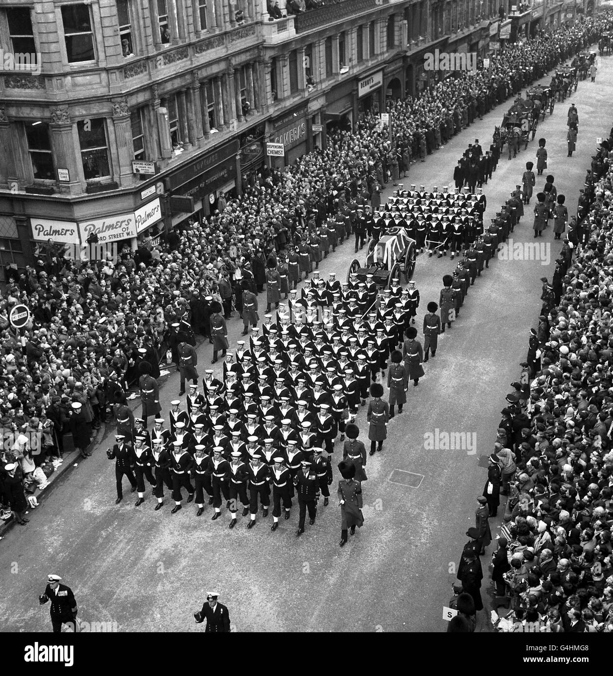 Les foules ont envie des trottoirs en adieu silencieux alors que la voiture à armes à feu portant le cercueil de Sir Winston Churchill est dessinée par les évaluations navales de Ludgate Hill à St. Pauls Catherddral pour le service funéraire. Banque D'Images