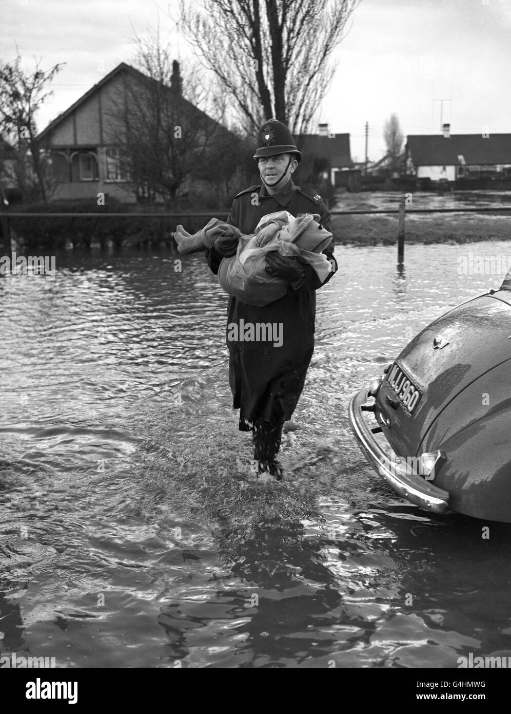 Un policier transporte un petit enfant par les inondations à l'île Canvey, dans l'Essex. Banque D'Images