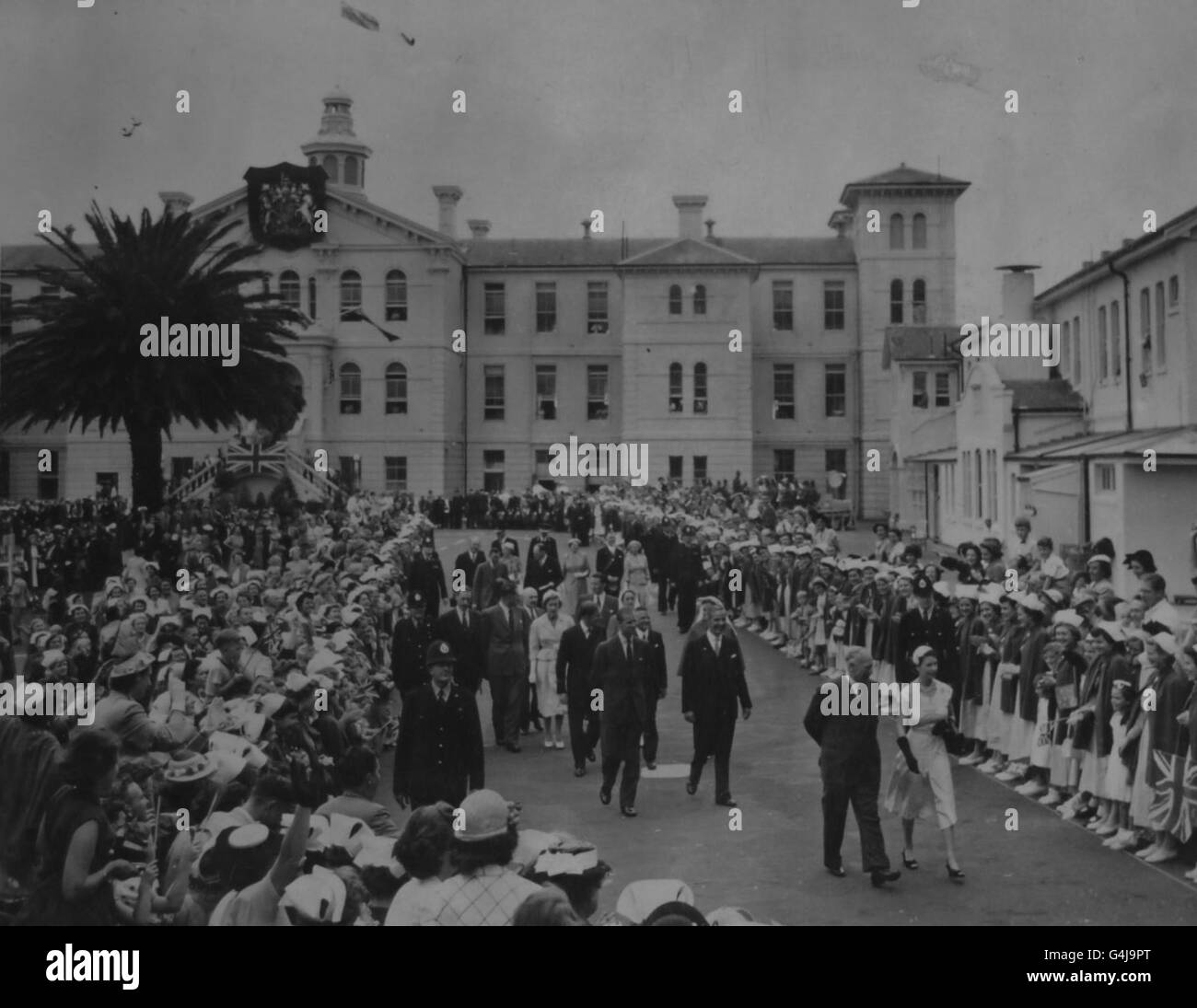 Des infirmières et des visiteurs se font la queue pour saluer la Reine et le duc d'Édimbourg qui sont vus à pied dans les jardins lorsqu'ils ont visité l'hôpital d'Auckland, en Nouvelle-Zélande. Banque D'Images