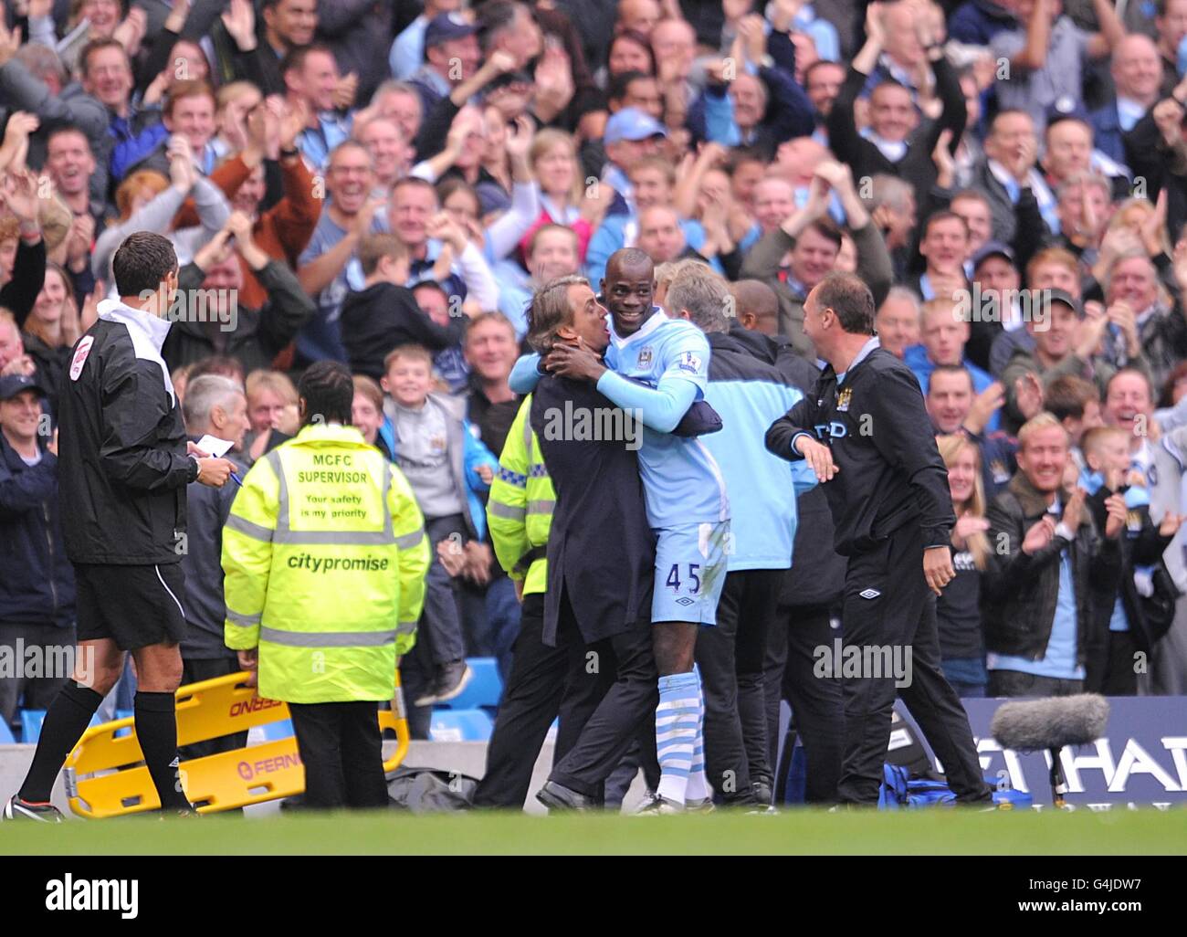 Mario Balotelli de Manchester City (au centre à droite) Fête avec le directeur Roberto Mancini (au centre à gauche) sur la ligne de contact après avoir obtenu le premier objectif du jeu Banque D'Images