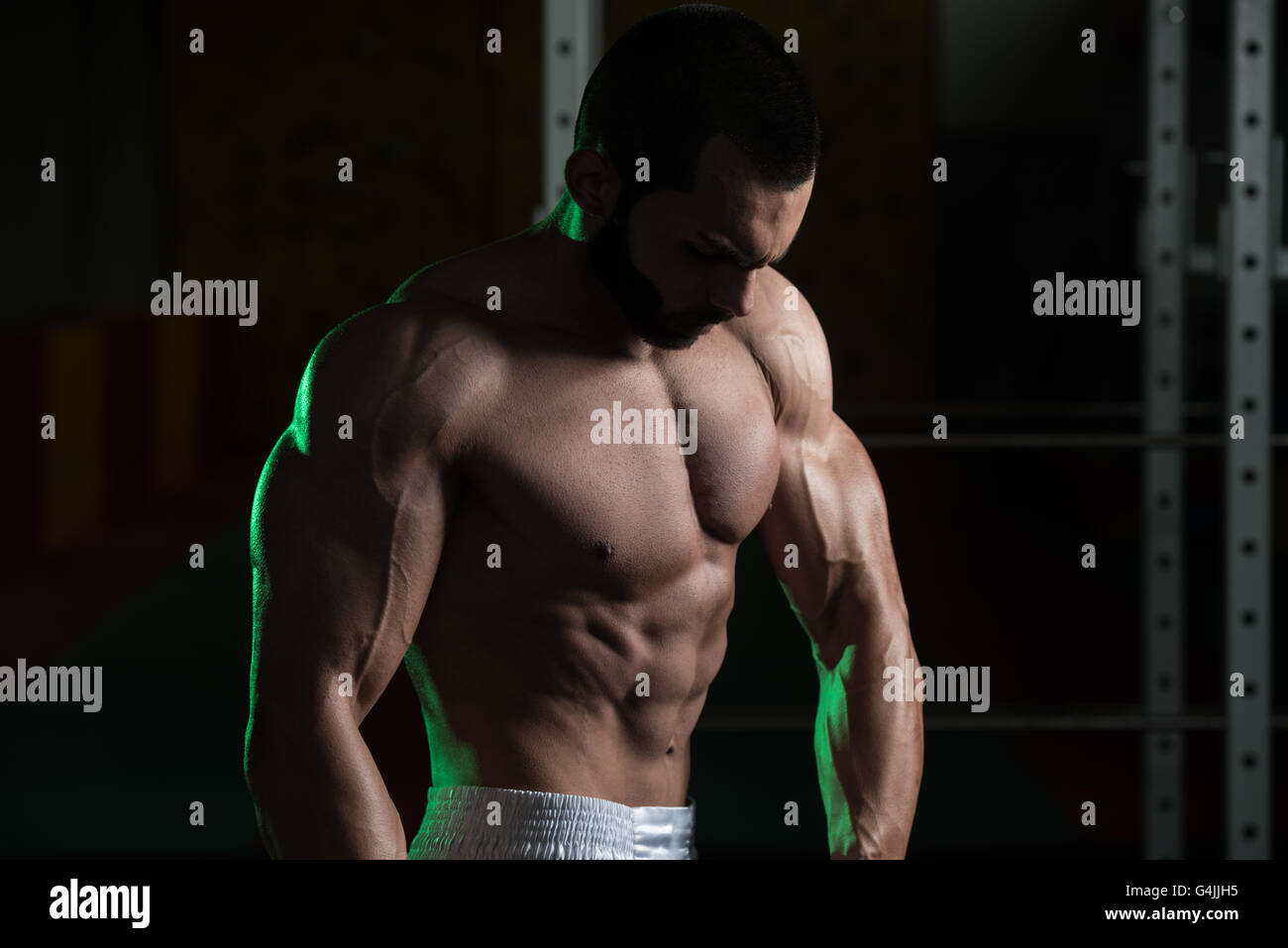 Jeune homme debout forte dans la salle de sport et Flexing Muscles musculaire - Fitness Model Posing Bodybuilder athlétiques exercices après Banque D'Images