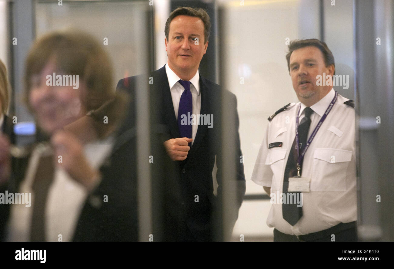 Le Premier ministre David Cameron (au centre) s'entretient avec le personnel des frontières du terminal 5 de l'aéroport d'Heathrow où il a vu les dernières technologies de reconnaissance faciale utilisées pour le contrôle des passeports. Banque D'Images