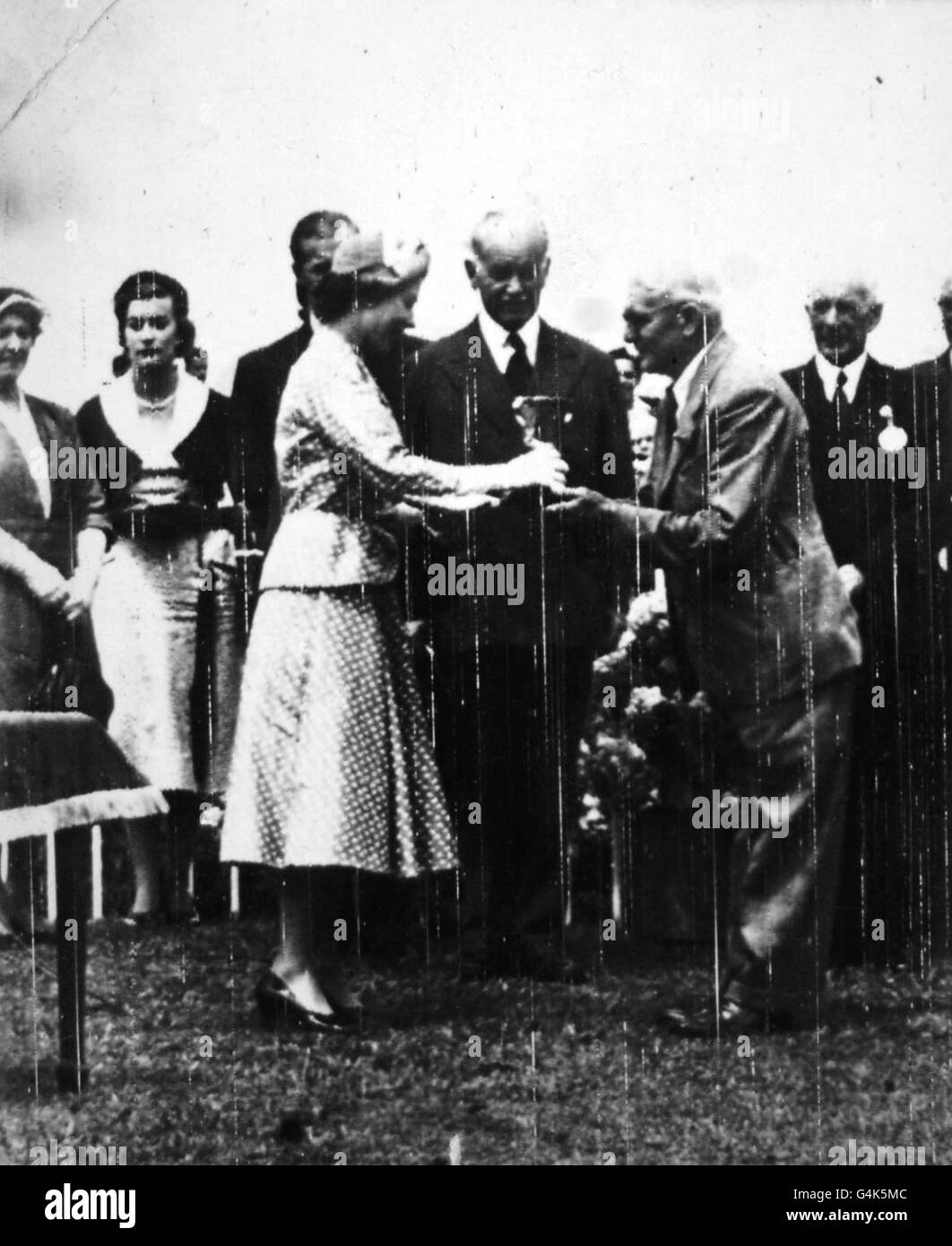 La Reine présente la coupe d'or à M. H.M Glazebrook, propriétaire de Coaltown, quand, avec le duc d'Édimbourg, elle a assisté à la journée d'ouverture de la réunion d'été du club de course d'Auckland à l'hippodrome d'Ellerslie, en Nouvelle-Zélande. Banque D'Images