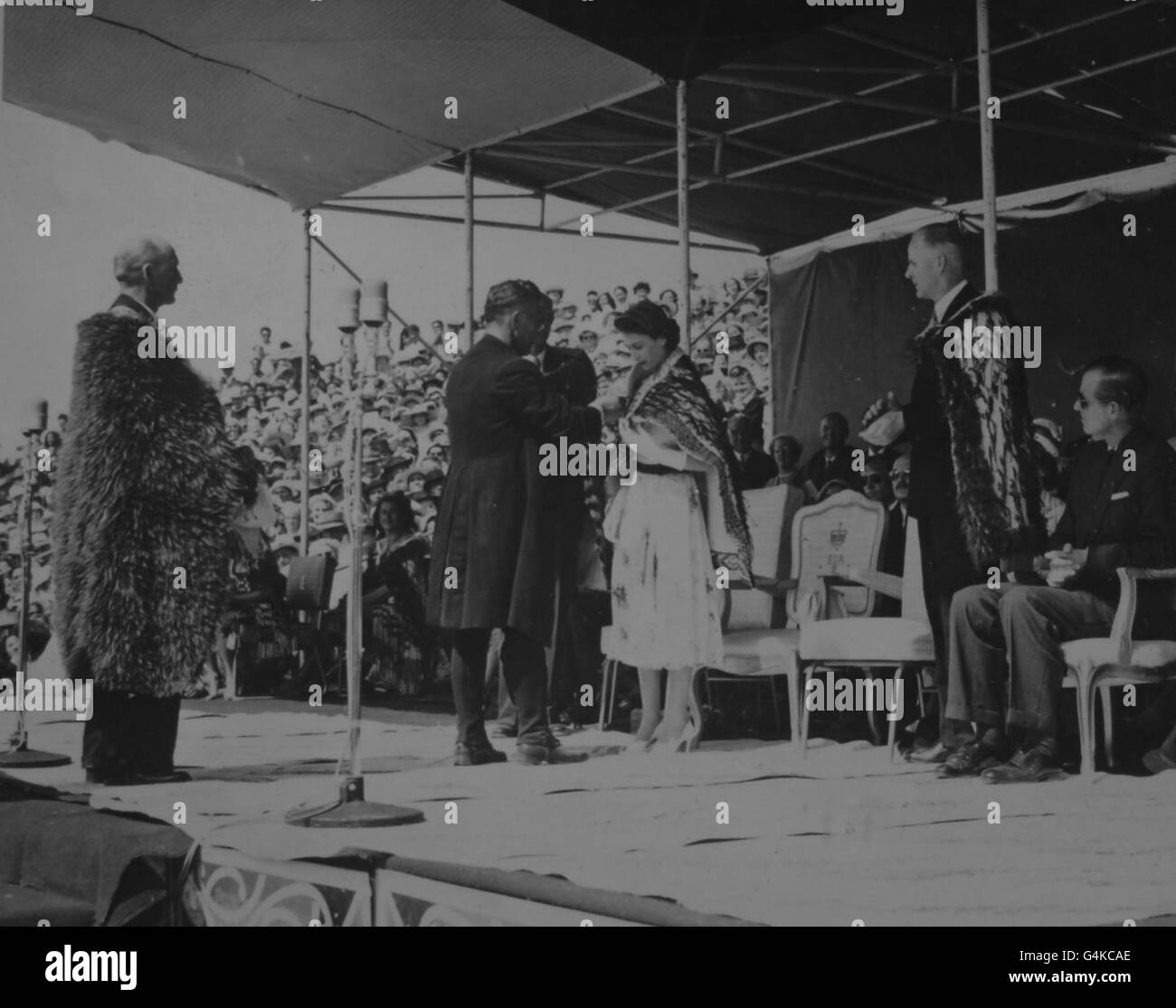 **balayage basse résolution de contact** la Reine est drapée par cérémonie avec le cloak Korowai par l'évêque d'Aotearo, le révérend droit Wirenu Panapa, à la réception maorie dans le parc Arawa, Rotorua, pendant la visite royale de Nouvelle-Zélande. Banque D'Images