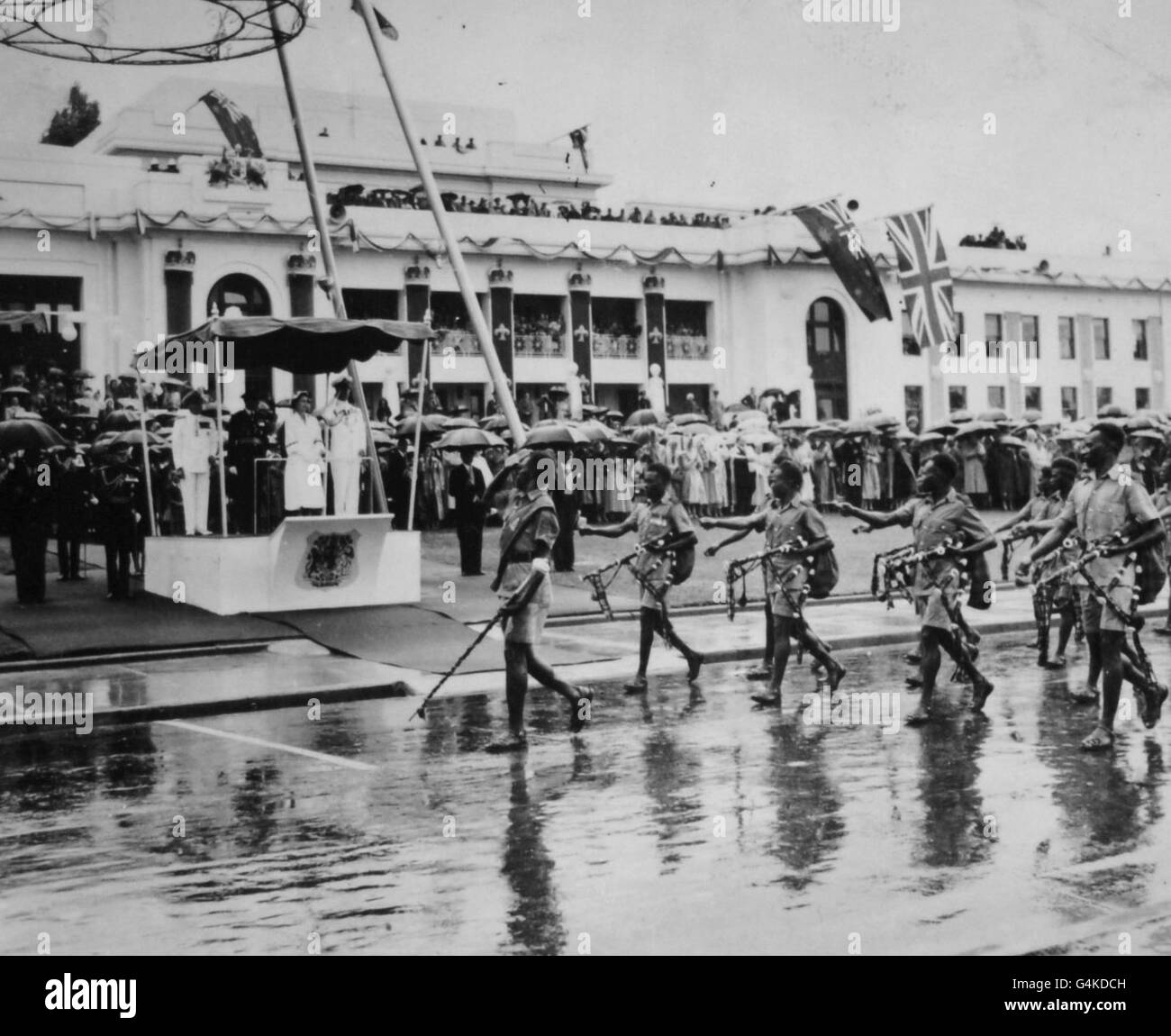 **numérisé de contact basse-résolution** la reine Elizabeth II, accompagnée du duc d'Édimbourg, prend le salut alors que les troupes de la Nouvelle-Guinée, des tuyaux sous bras, passent devant la pluie battante à l'examen des contingents des Services australiens à Canberra. Banque D'Images