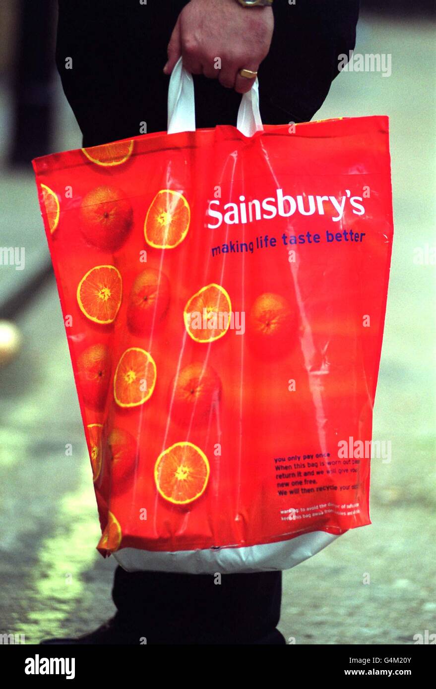 Un sac de transport en plastique Sainsbury dans les nouvelles couleurs du géant du supermarché. Dans le cadre de ses efforts pour revitaliser ses profits, Sainsbury a déversé les couleurs orange et marron ternes qu'elle utilise depuis les années 1970, les a remplacées par un sac plus brillant avec son nouveau logo. * 'Sainsbury's - rendre le goût de la vie meilleur'. 23/11/99: Les bénéfices de Sainsbury ont dégré de 29.5% car le groupe a investi massivement pour tenir ses propres dans les guerres des magasins. Sainsbury a déclaré que le coût du développement de campagnes pour aider à augmenter les ventes avait entraîné une baisse des bénéfices. Les coûts ont fait baisser ses bénéfices avant impôts à 297 millions dans les 28 semaines d'octobre Banque D'Images