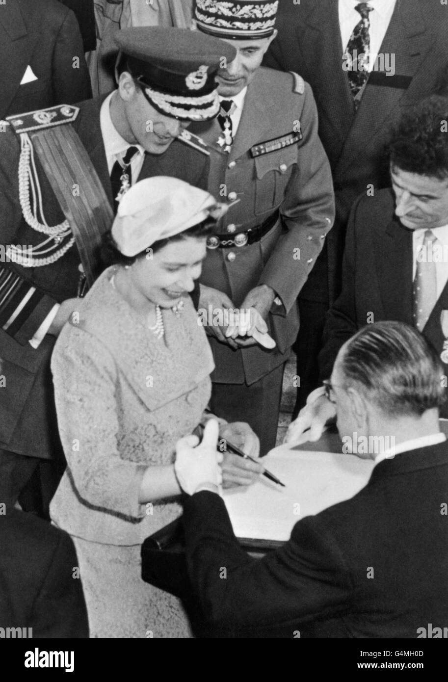 La reine Elizabeth II signe le livre d'or, conservé pour les visiteurs distingués, après avoir déposé une couronne à la tombe du Soldat inconnu à l'Arc de Triomphe, Paris. Le duc d'Édimbourg attend son tour pour signer. Banque D'Images
