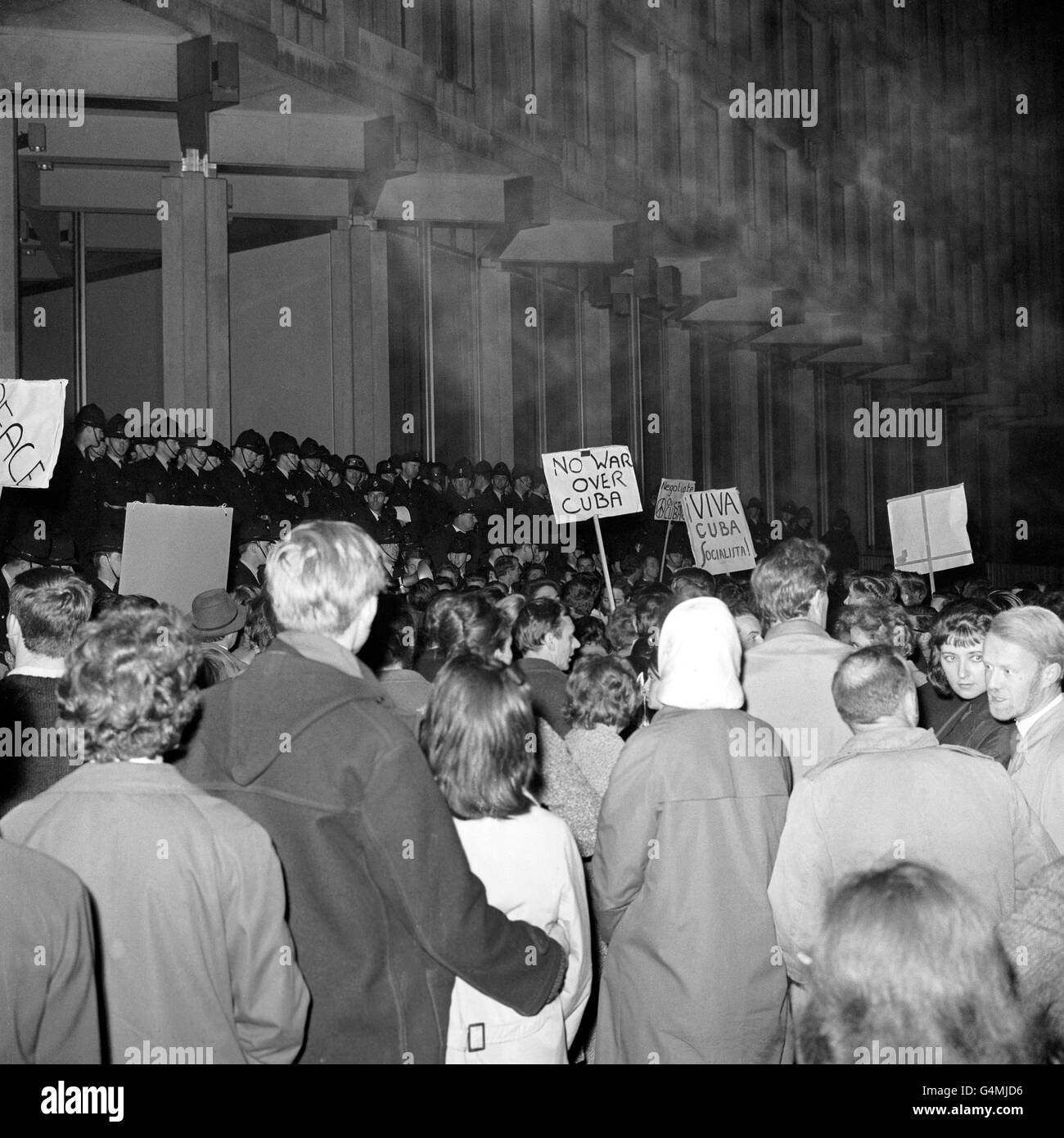 Des pancartes portant les mots « No War Over Cuba » sortent d'une foule de manifestants qui se dressent contre un cordon de police devant l'ambassade des États-Unis à Grosvenor Square, Londres. Les manifestants, estimés à 2,000 000, protestaient contre le blocus américain de Cuba. Banque D'Images