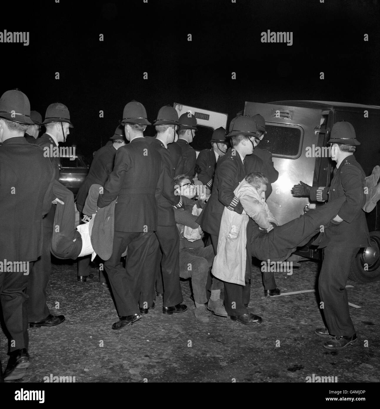 Des policiers élèvent de jeunes hommes dans des camionnettes de police en attente à Grosvenor Square, à Londres, lorsque 2,000 manifestants ont convergé vers l'ambassade des États-Unis pour protester contre le blocus américain de Cuba. Banque D'Images