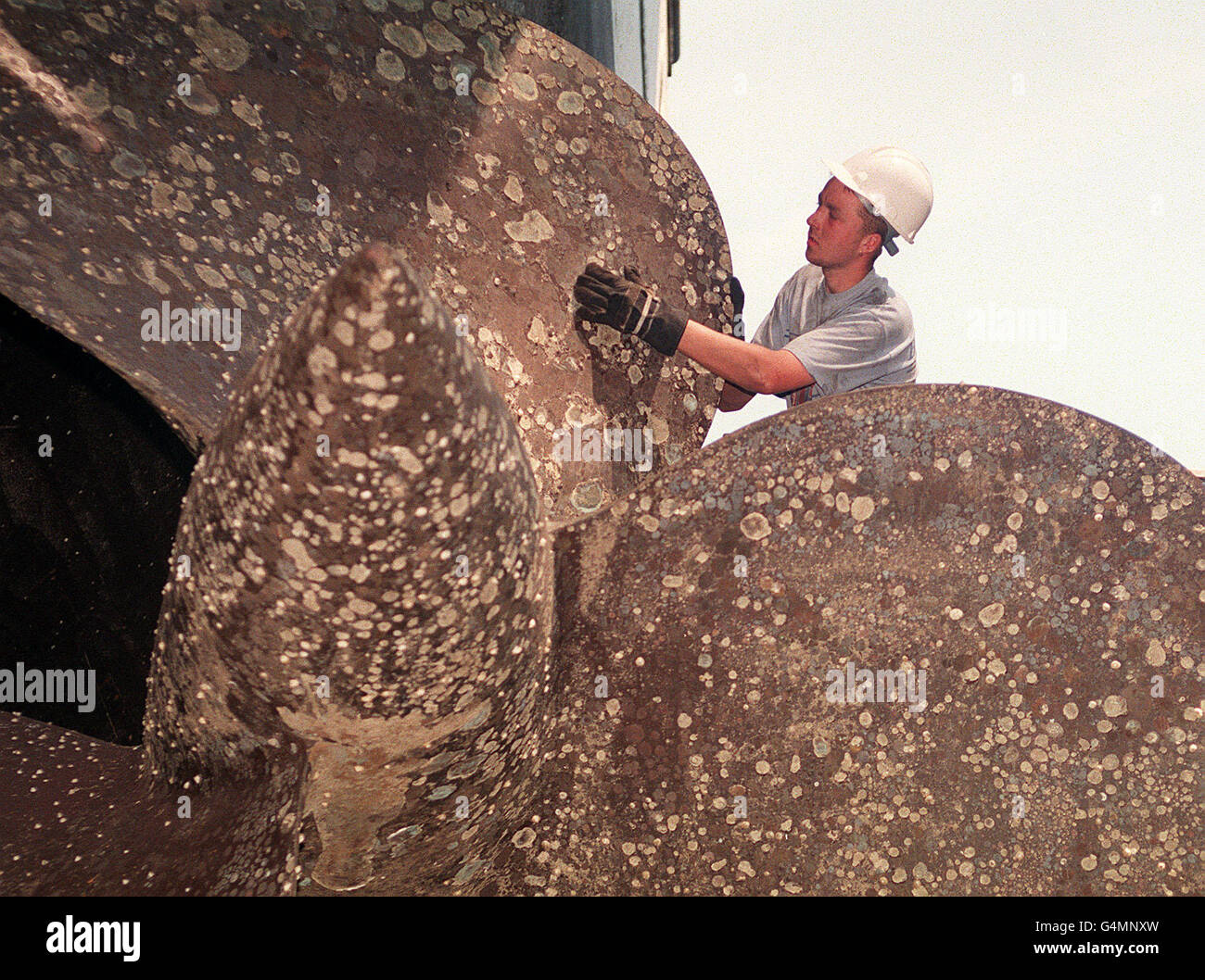 Un travailleur vérifie l'hélice du croiseur HMS Belfast alors qu'il est en cale sèche dans la base navale de Portsmouth pour y faire un réajustement.Le croiseur, qui a vu le service pour la dernière fois à la fin des années 60, n'est pas en cale sèche depuis 18 ans. Banque D'Images