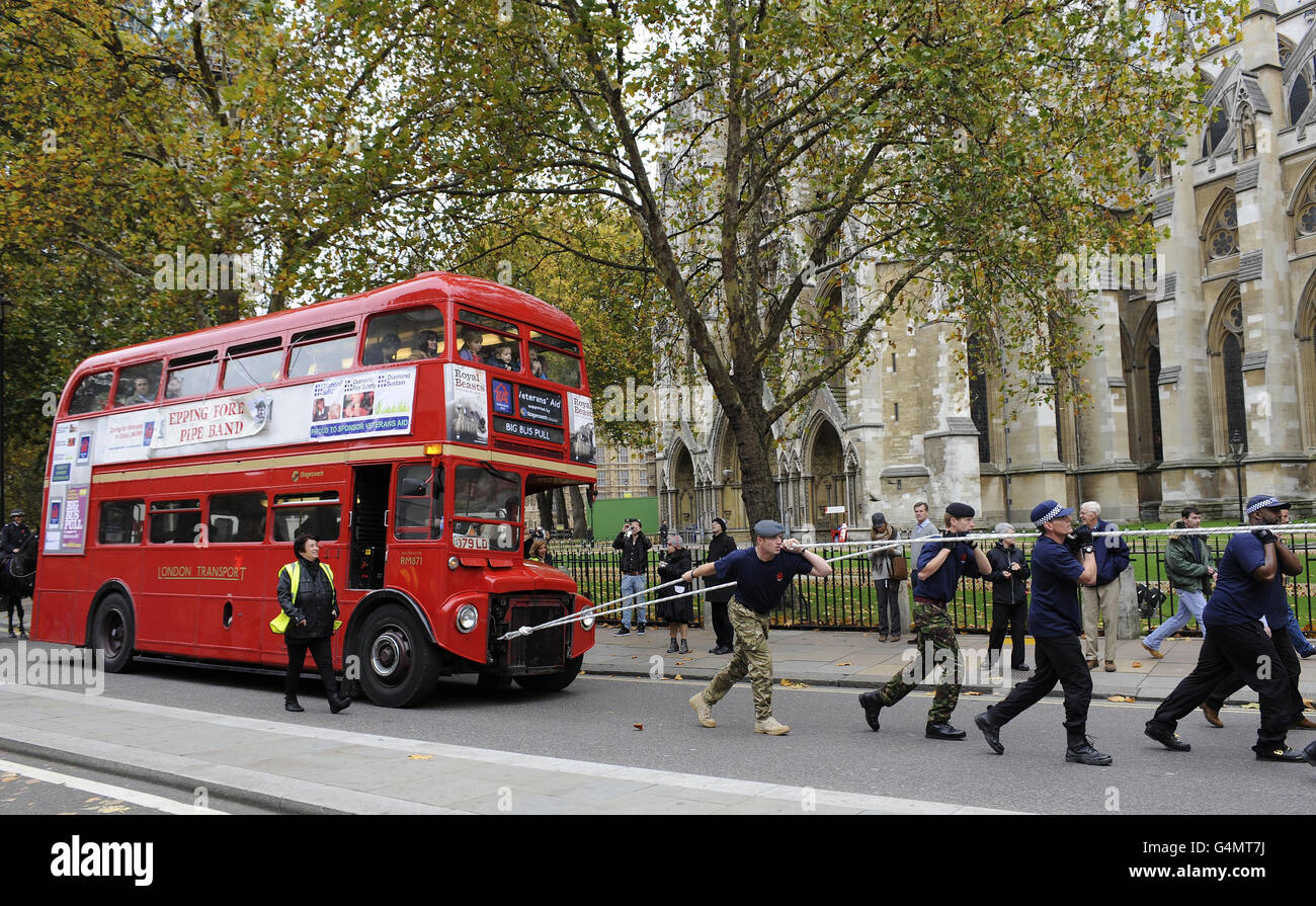 Une équipe de 10 policiers et de 10 membres des forces armées tirent un bus à impériale à pleine charge sur 1,5 kilomètre à travers Westminster, pour recueillir des fonds pour la Veterans Aid Charity. Banque D'Images