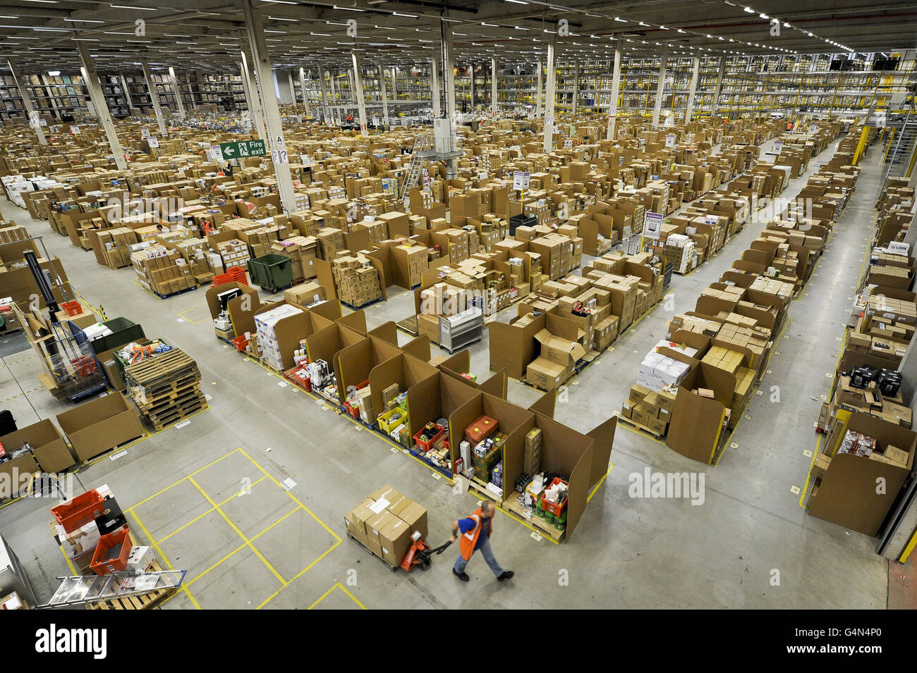 Un employé du centre de distribution Amazon de Swansea tire un chariot à  pompe au-delà de milliers de bacs de stockage en carton, qui contiennent  des marchandises à expédier dans le monde