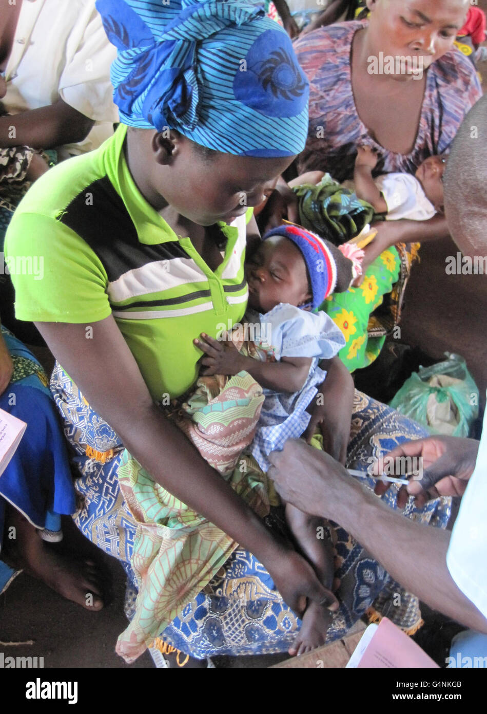 Une mère tient son enfant alors qu'ils sont vaccinés par des agents de santé à Chifuchambewa, un village agricole dans la brousse africaine à 100 milles à l'ouest du lac Malawi, en Afrique. Banque D'Images