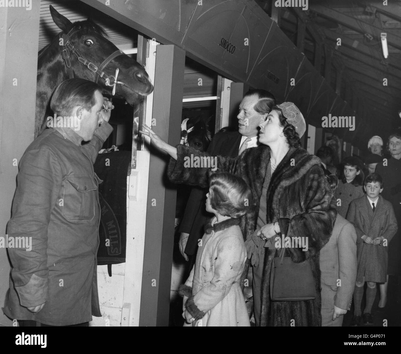 La reine Elizabeth II et la princesse Anne voient les chevaux de cirque dans leurs étals lorsqu'ils ont assisté à la représentation de Bertram Mills Circus à Olympia, Londres. Cyril Mills est à gauche de la Reine. Banque D'Images