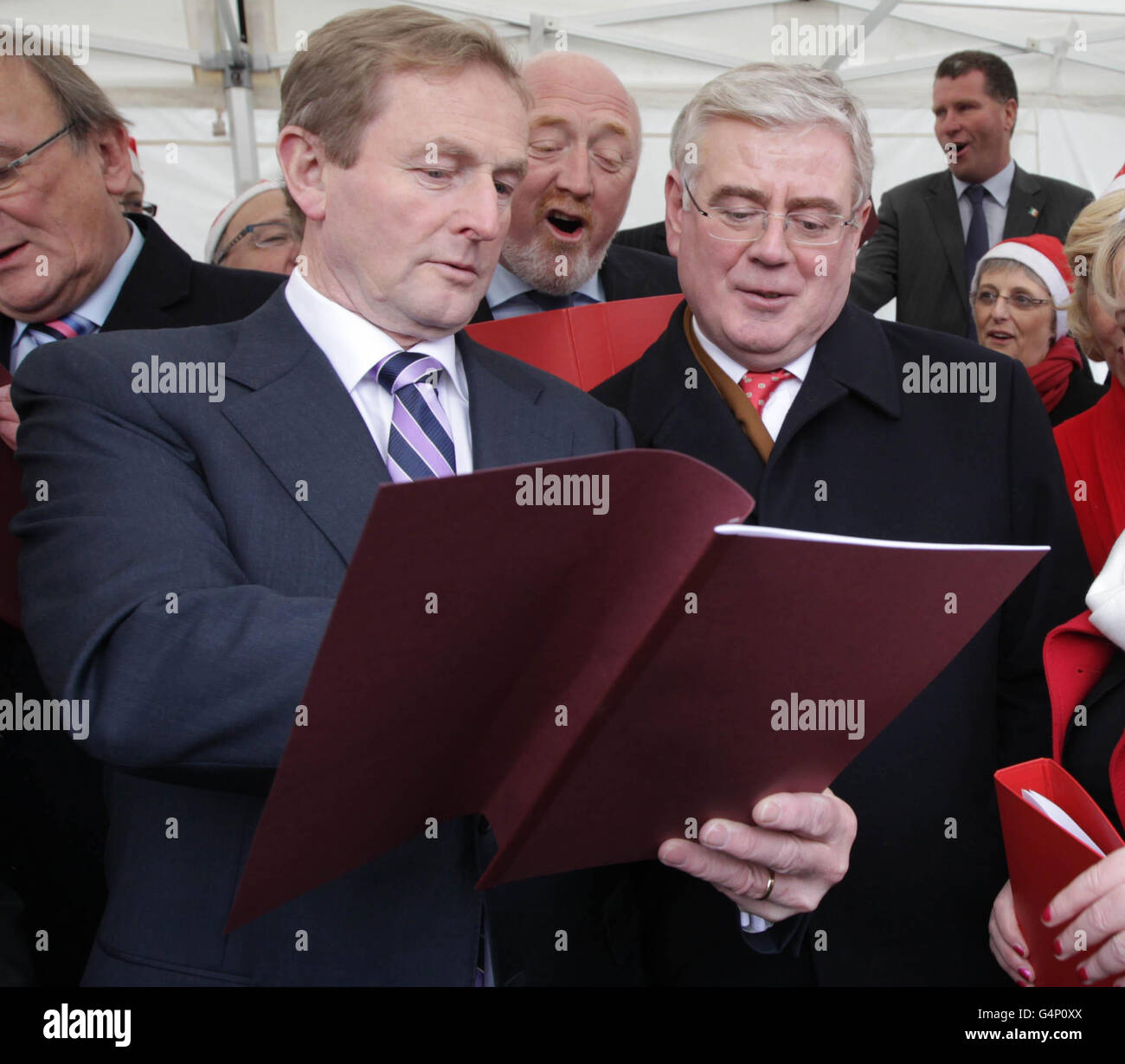 Taoiseach Enda Kenny (à gauche) et Tanaiste Eamon Gilmore (à droite) chantant des chants de Noël devant Leinster House à Dublin après les feux d'arbre de Noël où Ceann Comhairle Sean Barrett. Banque D'Images