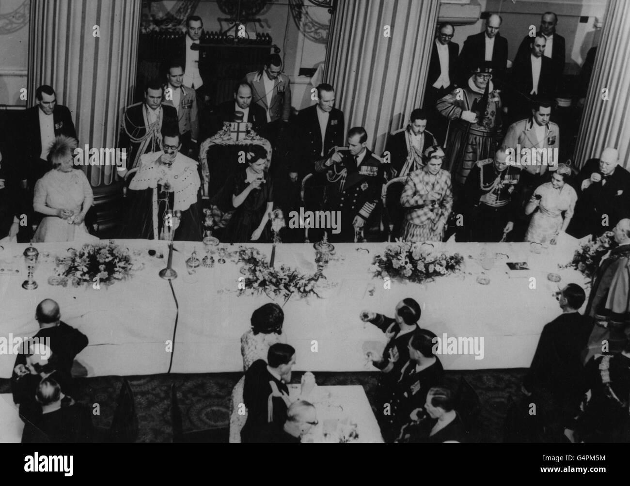 La reine Elizabeth II lève son verre dans un toast lors du déjeuner de la « maison de bienvenue » donné par le maire Lord et la Corporation de Londres à la Mansion House, ville de Londres, pour marquer le retour de la visite du Commonwealth. De gauche à droite; la Reine mère; Sir Noel Bowater (Lord Mayor; la Reine; le duc d'Édimbourg; Lady Bowater (Lady Mayoress); le duc de Gloucester; la princesse Margaret et Sir Winston Churchill. Banque D'Images