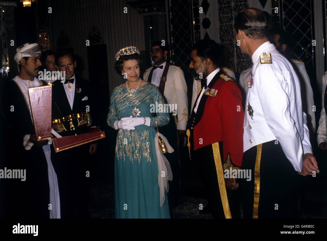 La reine Elizabeth II et le duc d'Édimbourg échangent des cadeaux avec le sultan d'Oman, le sultan Qaboos bin dit, en veste rouge, lors d'un dîner au palais Muscat d'Oman. Banque D'Images
