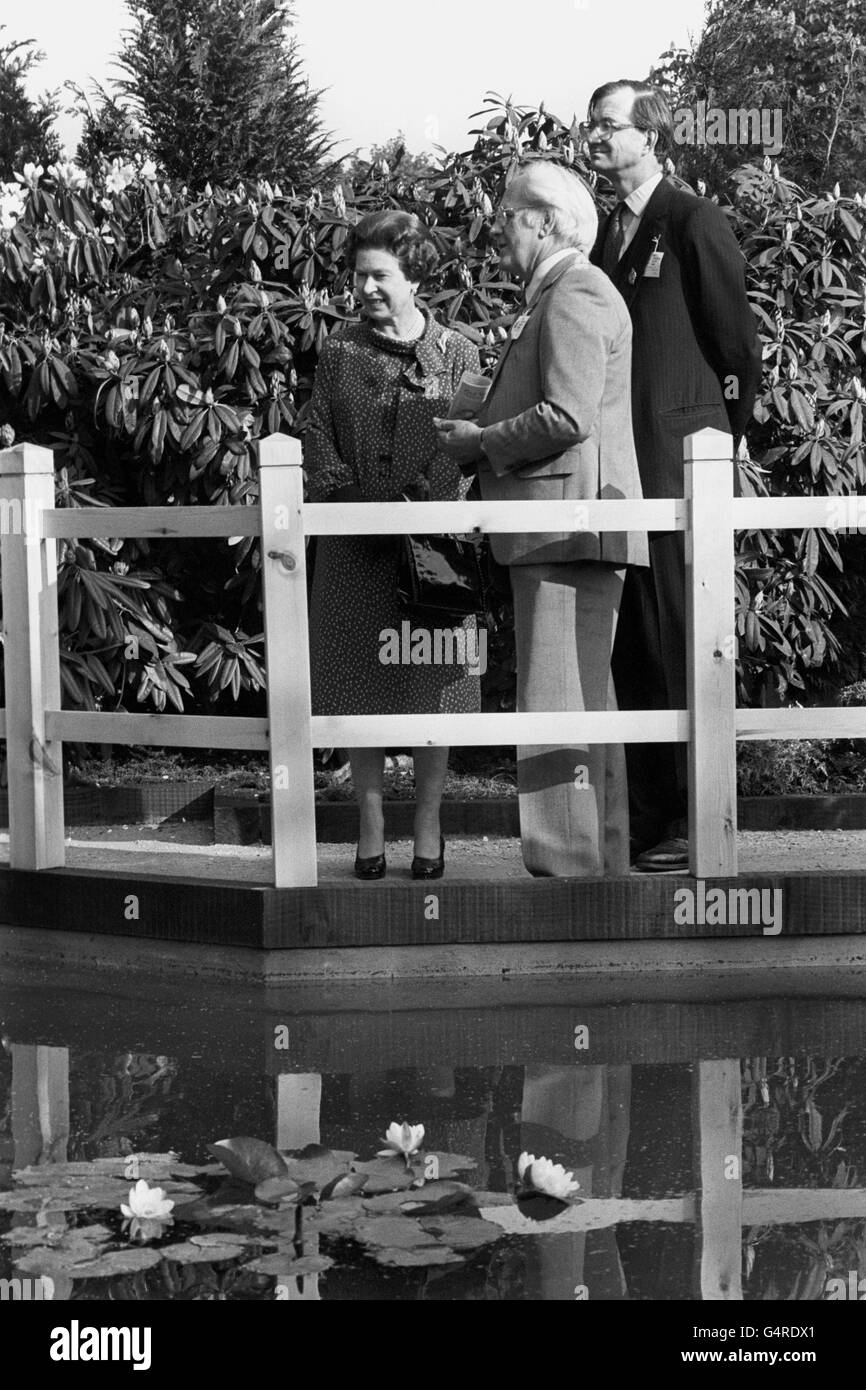 La reine Elizabeth II voit une scène aquatique dans un jardin de l'avenue principale du Chelsea Flower Show, l'exposition de Paul Temple (au centre) avec le président de la Royal Horticultural Society, Robin Herbert (à droite). Banque D'Images