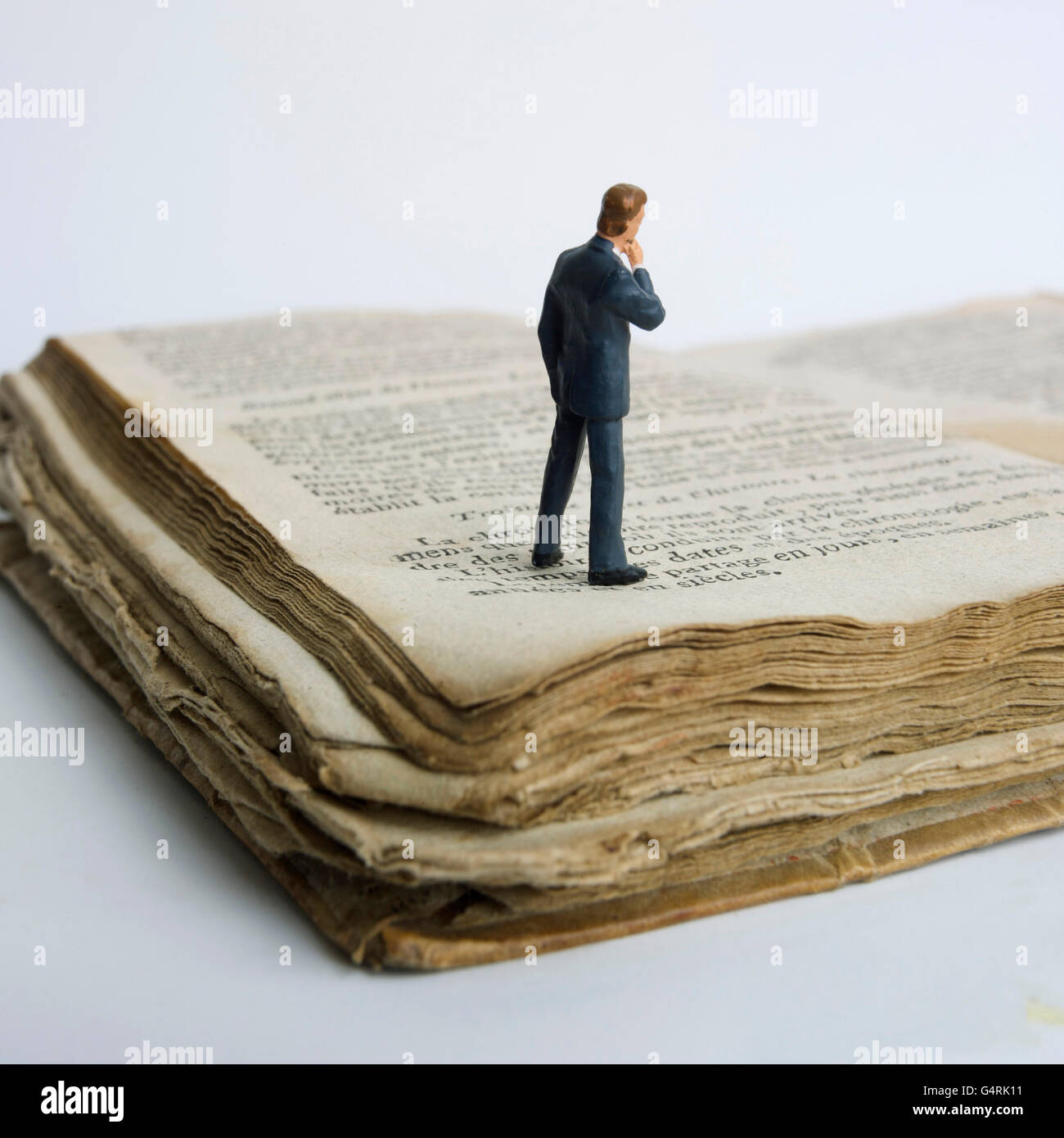 L'homme, miniature, figurine, debout sur un vieux livre Banque D'Images