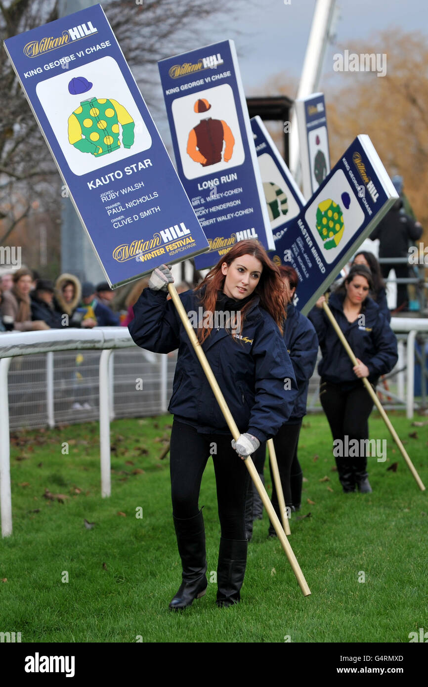 Courses hippiques - le William Hill Winter Festival 2011 - King George VI Steeple Chase - Kempton Park.Les filles Hill's Angels tiennent des pancartes avec des informations sur les entrées de course individuelles avant le King George VI Steeple Chase Banque D'Images