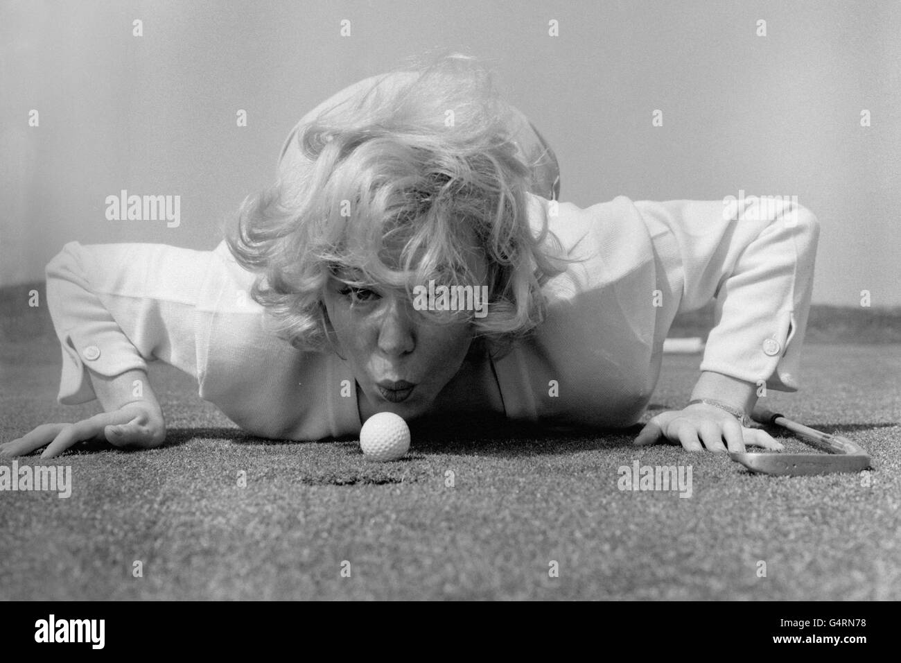 La chanteuse Kathy Kirby souffle sa balle de golf plus près du trou sur le parcours de golf Old Links, Lytham St. Anne's. La chanteuse a visité le cours pendant les pauses de son été à Blackpool. Selon le professionnel local, elle a fait de bons progrès depuis qu'elle a commencé à jouer le sport. Kathy a dit «J'ai toujours été intéressé par le jeu, mais jamais eu rond à l'essayer. Beaucoup d'autres gens d'affaires de spectacle semblent prendre le golf, donc je pensais que je pourrais aussi bien rejoindre en. Banque D'Images