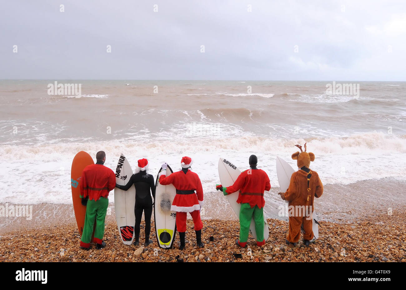Surfeurs (de gauche à droite) Oliver Harvey, James Ranson, Martin Drake-Knight, Rob Drake-Knight et Chris Mannion surfent en robe de Noël, à Grange Chine, sur l'île de Wight. Banque D'Images