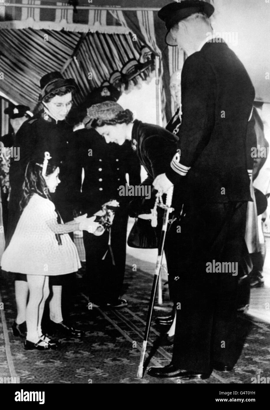 Une petite fille présente un bouquet de fleurs à la princesse Elizabeth, tandis que le duc d'Édimbourg se tient à côté, lors de sa visite à Kingston, en Ontario. Banque D'Images