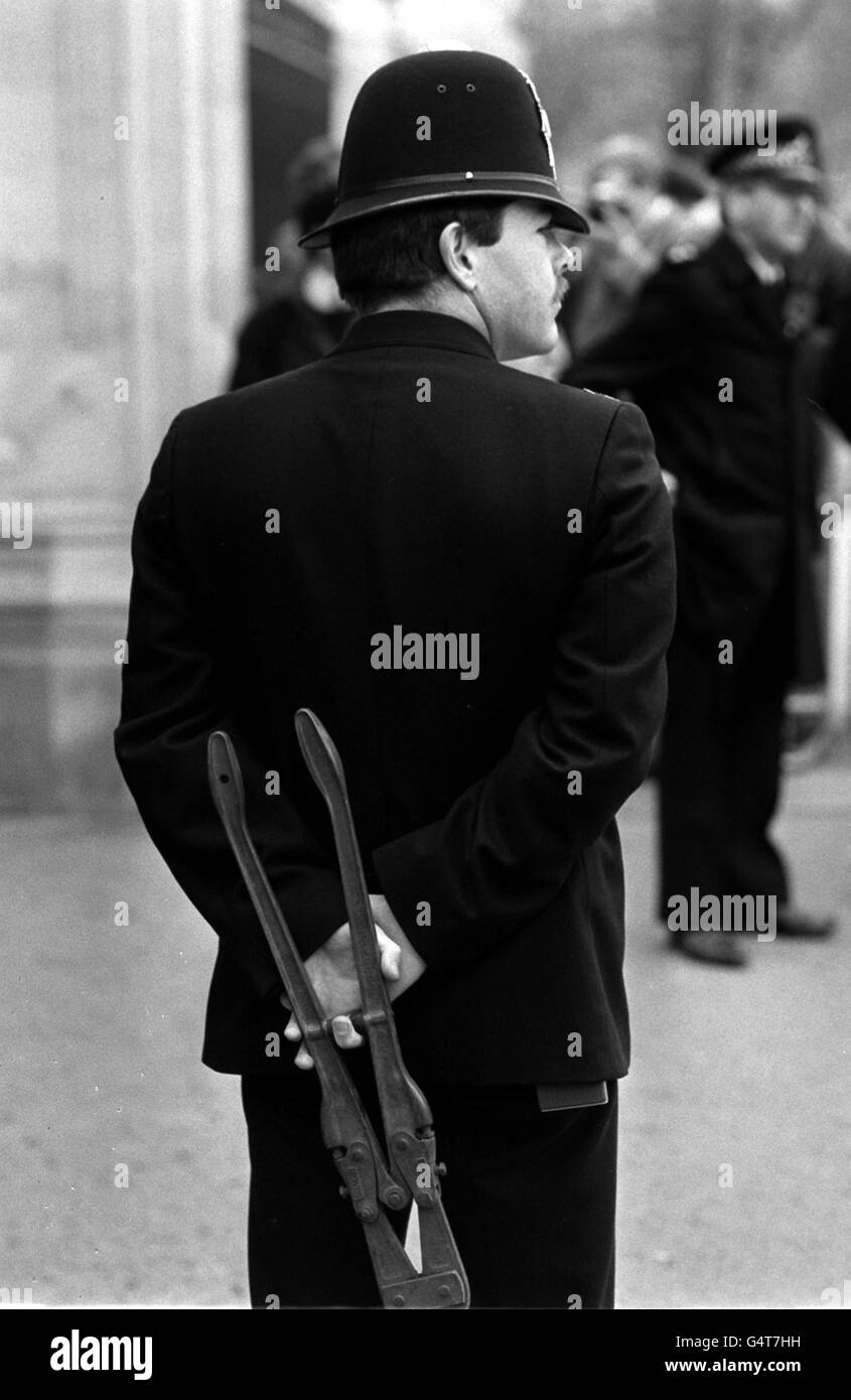 Un policier tient des couteaux à boulon derrière son dos avant de libérer un groupe de manifestants qui se sont enchaînés aux portes de Buckingham Palace à Londres, pour protester contre les plans du gouvernement visant à interdire la promotion de l'homosexualité par les autorités locales. Banque D'Images