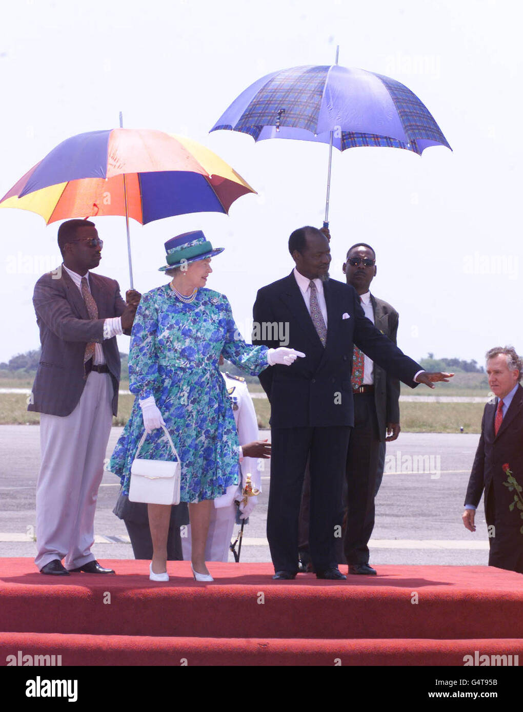 La reine Elizabeth II de Grande-Bretagne et le président Joaquim Chissano (à droite) du Mozambique sont protégés par des parasols à son arrivée à l'aéroport de Maputo.Sa visite guidée de la capitale du pays fait suite à des visites au Ghana et en Afrique du Sud.* c'était la première visite de la Reine au plus récent membre du Commonwealth, un pays qui se remet encore de 16 ans de guerre civile. Banque D'Images