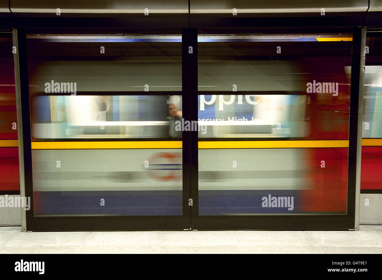 Un train franchit des barrières de verre installées sur les plates-formes de la station de métro Canary Wharf, conçue par les architectes Fosters and Partners, désormais ouverte dans le cadre de l'extension de la ligne Jubilee du métro de Londres. Banque D'Images