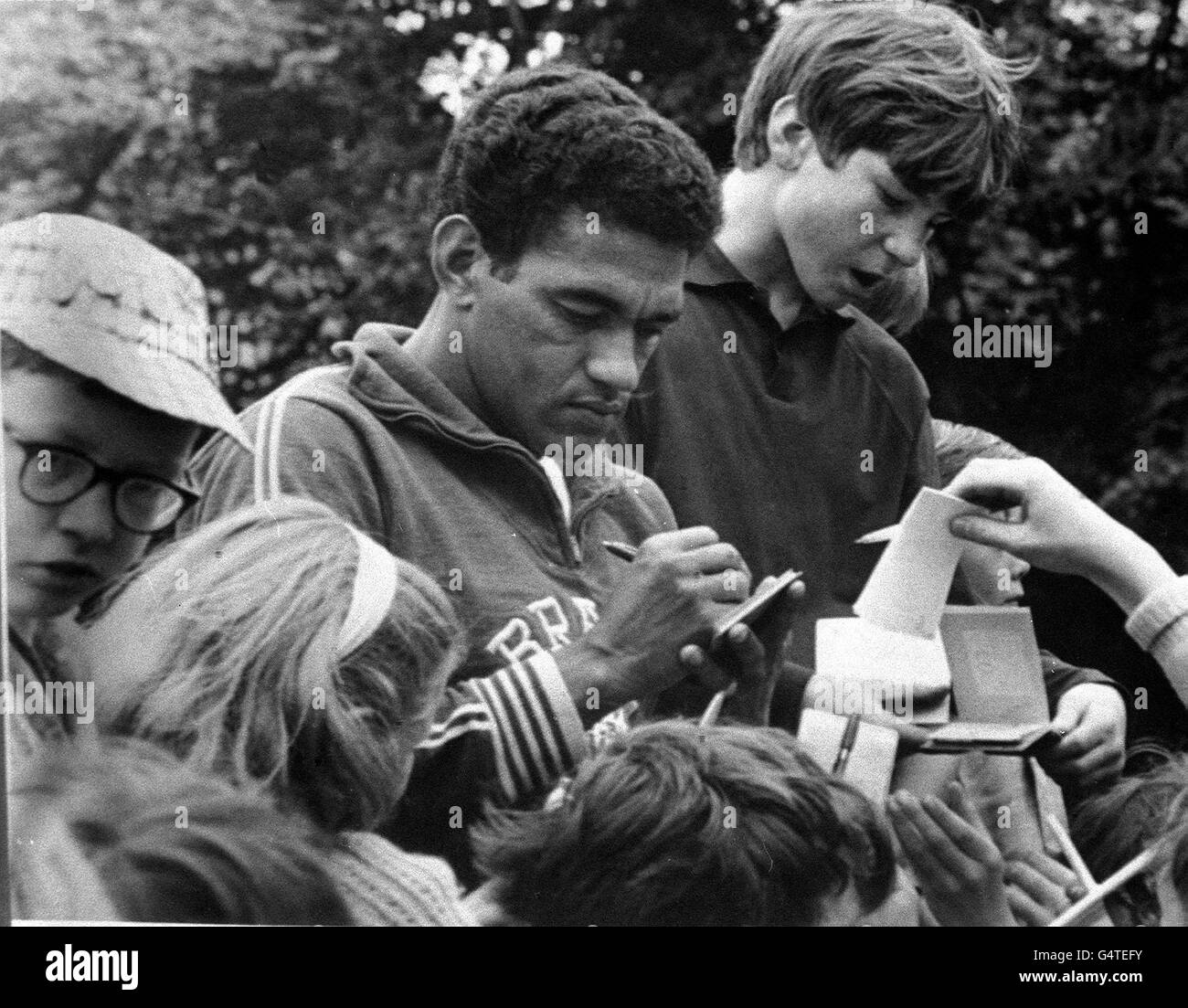 « Little Bird » Garrincha, la star brésilienne aigre assiégée par de jeunes chasseurs d'autographes, devant l'hôtel Lymm, Cheshire, où il séjourne avec le reste de l'équipe brésilienne de la coupe du monde. L'équipe joue la Bulgarie à Everton le 12 juillet 1966. Banque D'Images