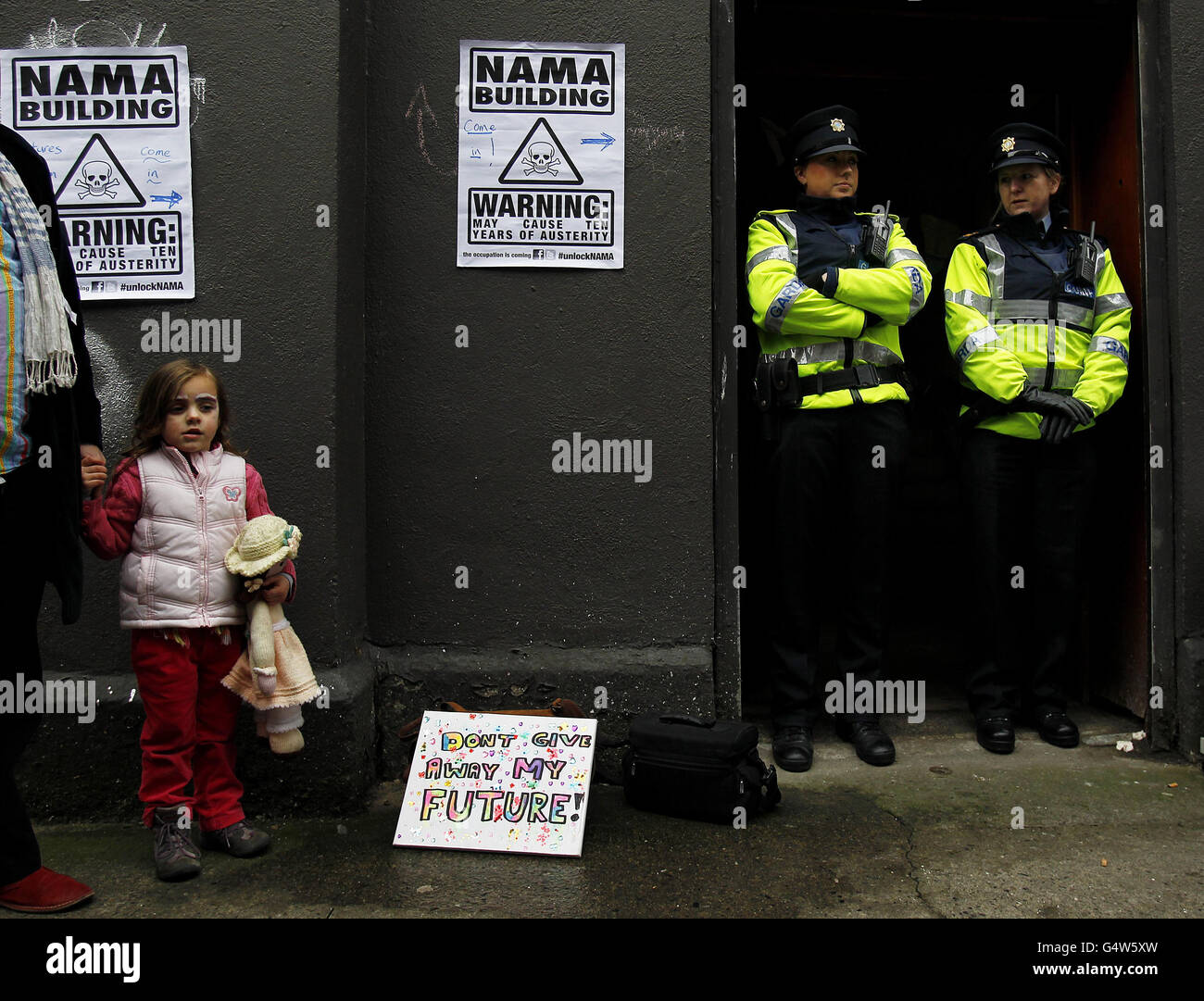 Orla Jennings, âgée de quatre ans, tient la main de son père Peter Harris à l'extérieur d'un bâtiment occupé par des membres de Unlock NAMA sur la Great Strand Street à Dublin, alors que les manifestants du groupe ont pris la propriété, que l'on croit être sous la propriété de NAMA, et l'ont ouvert au public. Banque D'Images