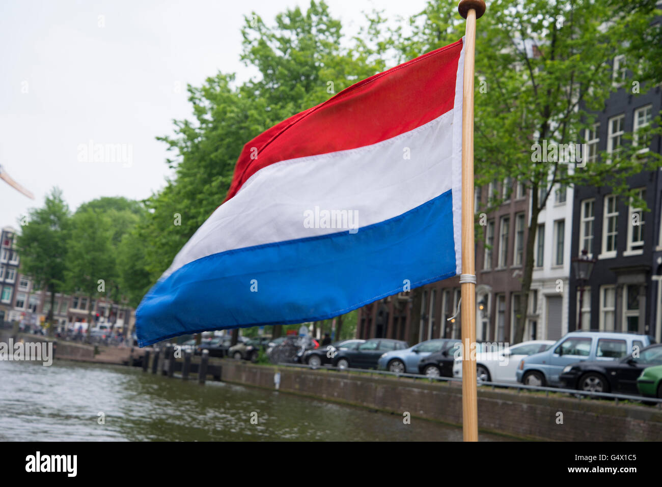 Drapeau national des Pays-Bas vole sur un bateau sur l'un des 3 principaux grands canaux semi-circulaires à Amsterdam. Banque D'Images