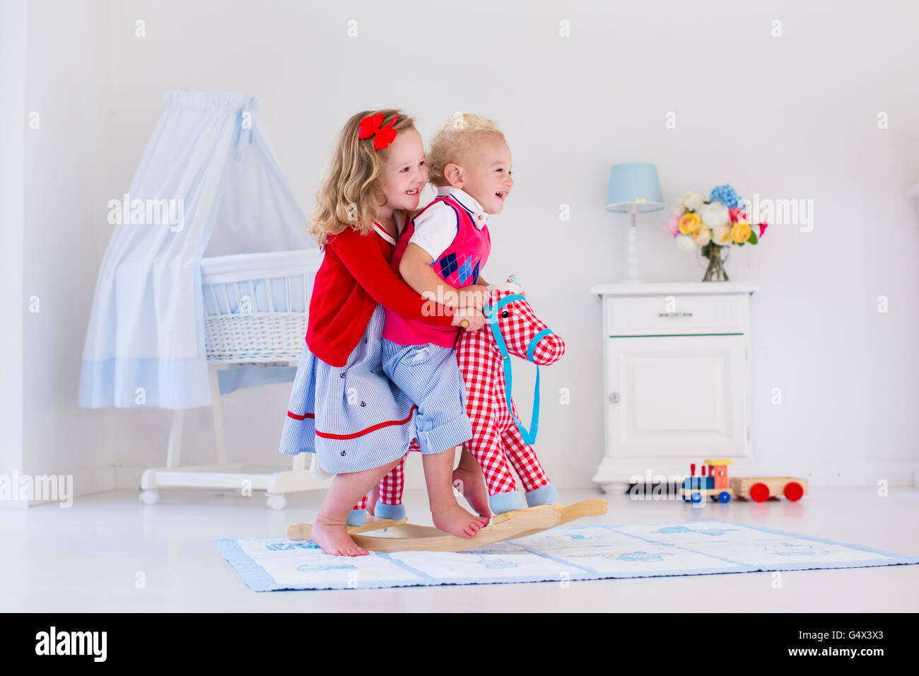 Deux enfants jouent à l'intérieur. Équitation cheval à bascule jouet pour enfants. Garçon et fille jouer à la garderie ou à la maternelle. Banque D'Images